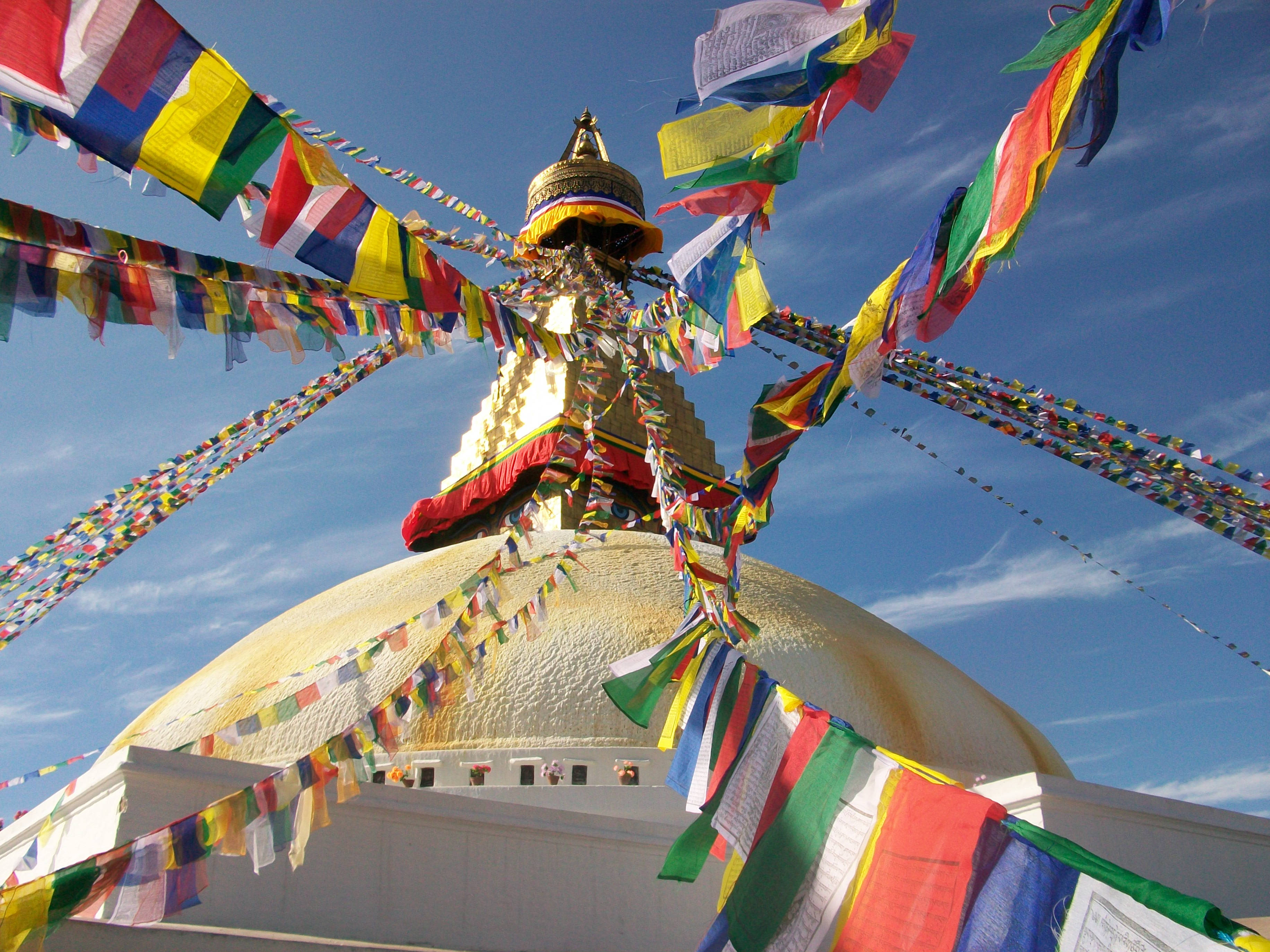 Nepal 桌布 壁紙 — 金色佛塔圓頂，頂端飄揚著經幡，映襯著清澈的藍天。