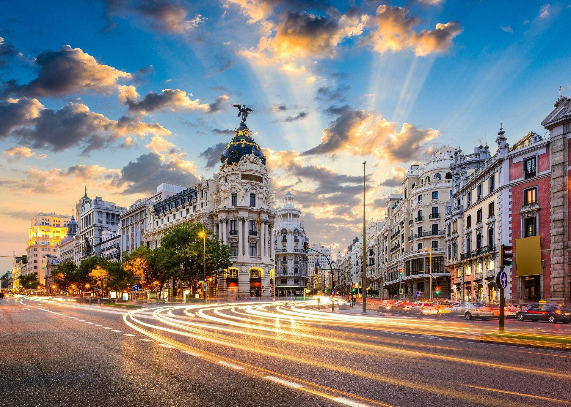 Madrid 桌布 壁紙 — 金色光線劃過繁華的城市街道，在日落時分照亮了華麗的建築和充滿活力的交通痕跡。