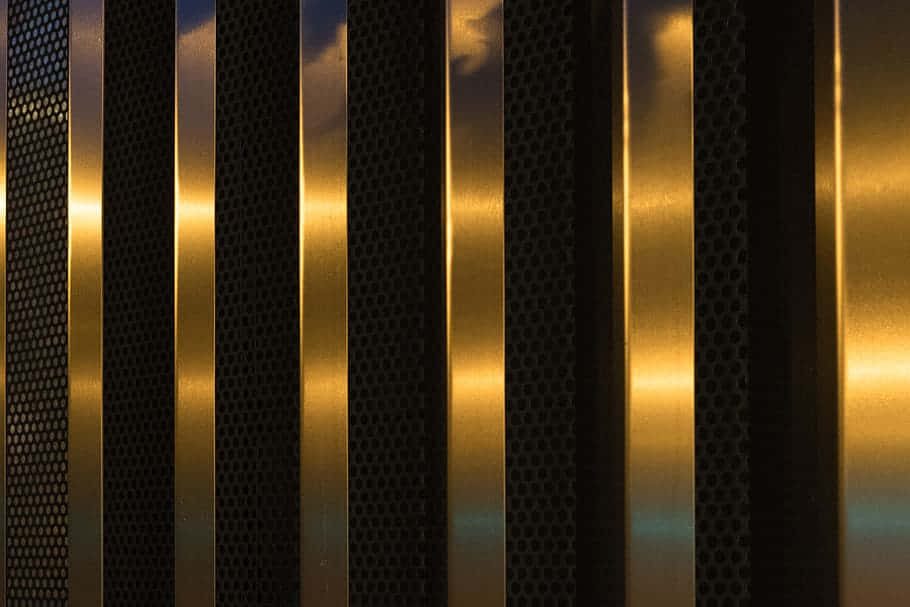 Elegant Black And Gold 桌布 壁紙 — 金色光線穿過帶有穿孔紋理的垂直金屬板條，映襯著暮色天空。