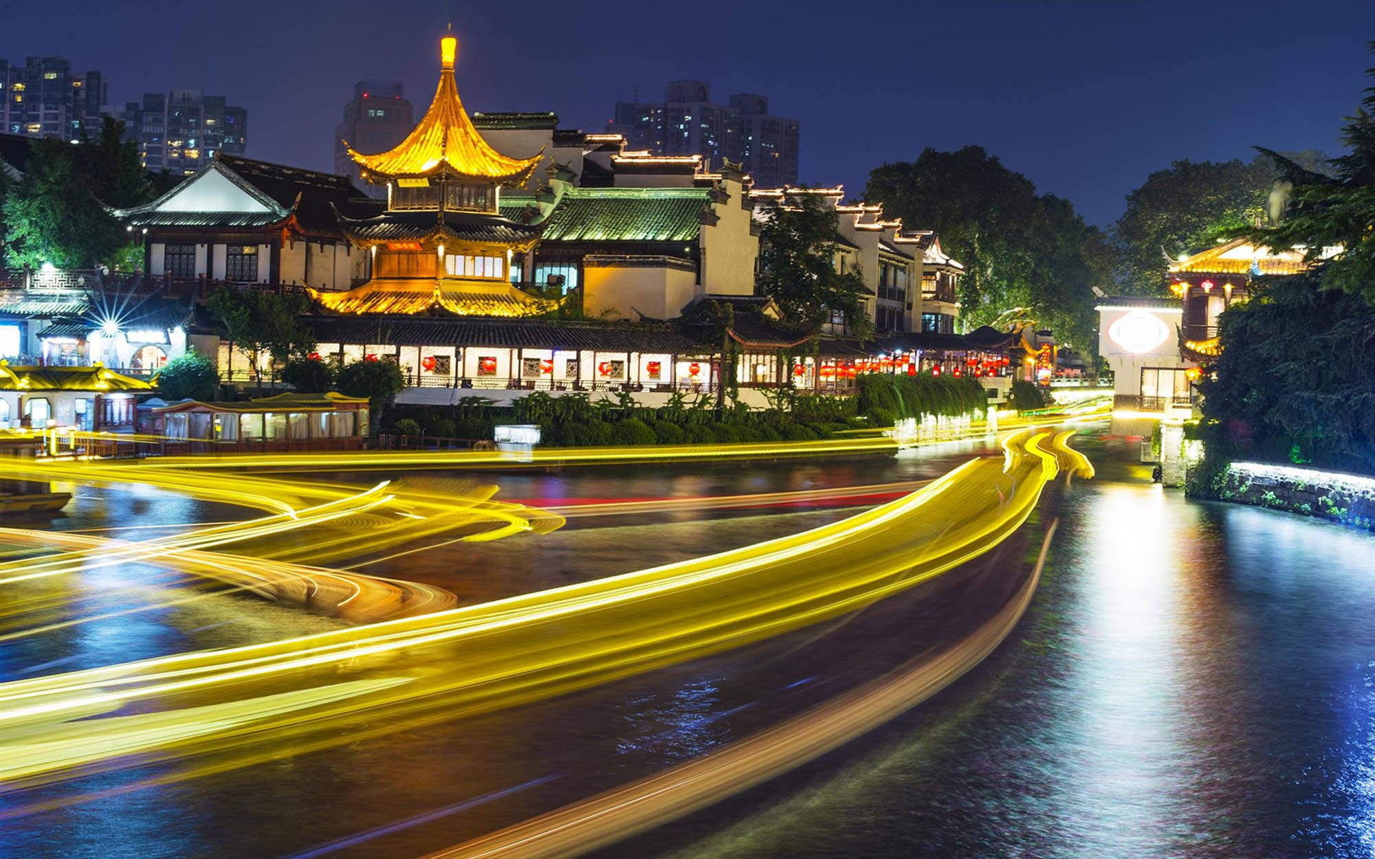 Nanjing 桌布 壁紙 — 金色光跡在夜晚濕漉漉的街道上劃過，下方是燈火輝煌的傳統中式建築。