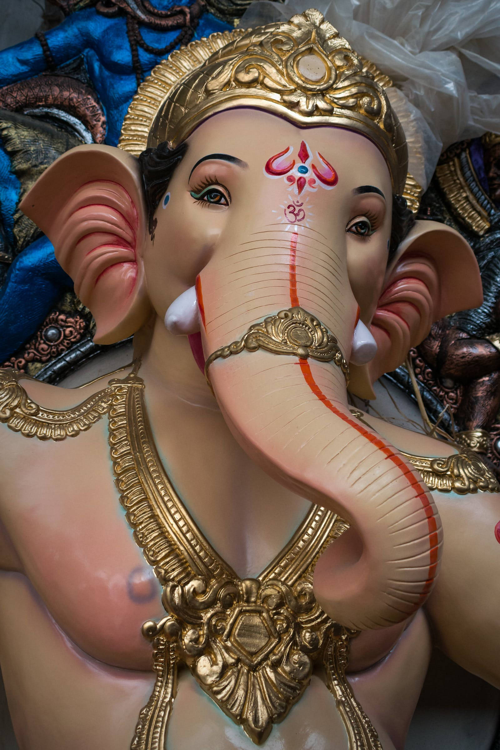 Vinayaka 桌布 壁紙 — 金色和粉紅色象頭神雕像的特寫，飾有精緻珠寶和紅色標記。