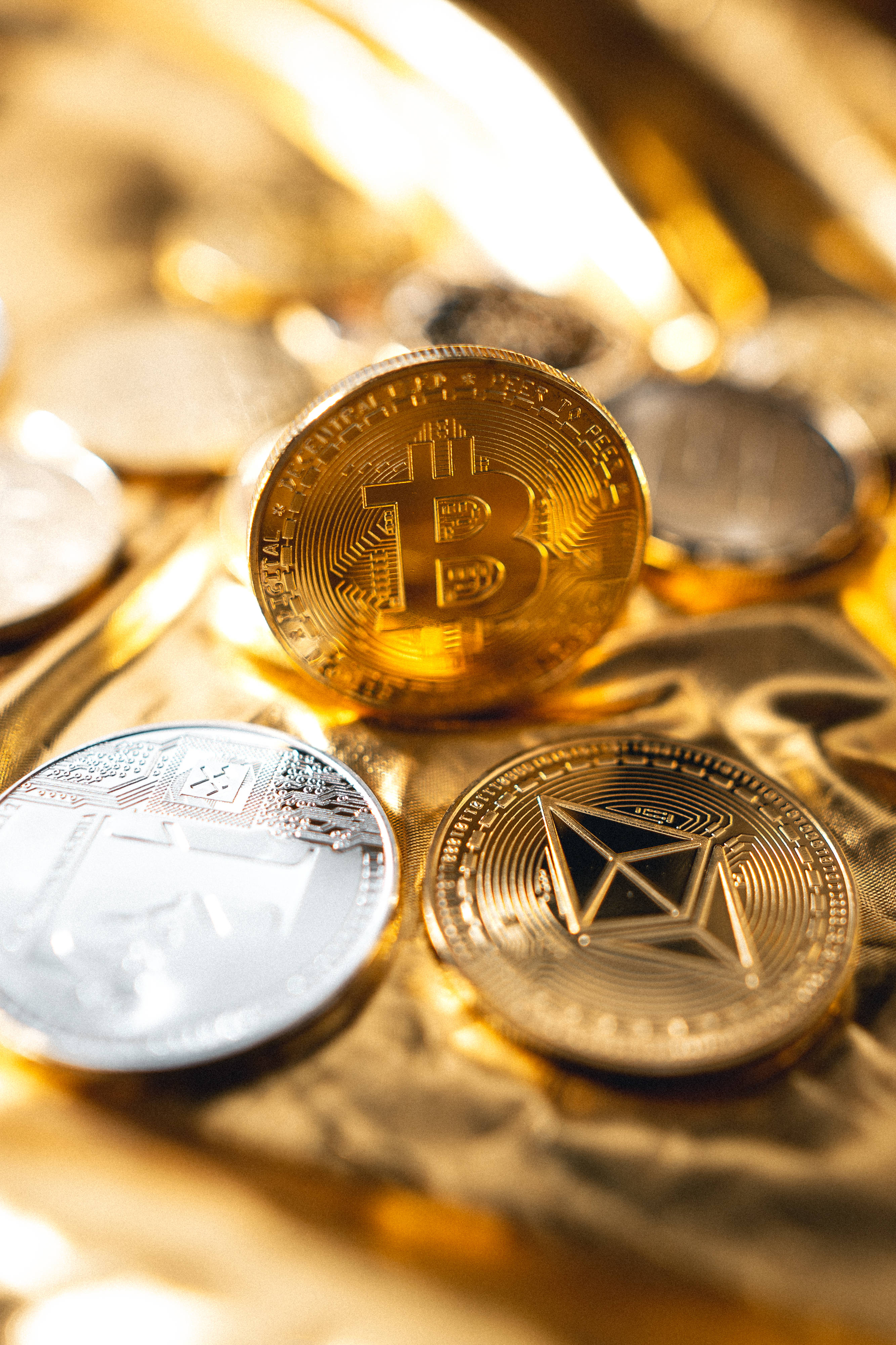 Cryptocurrency 桌布 壁紙 — 金色和銀色的加密貨幣硬幣，帶有比特幣和以太坊符號，在溫暖的燈光下放置在豪華的金色布料上。