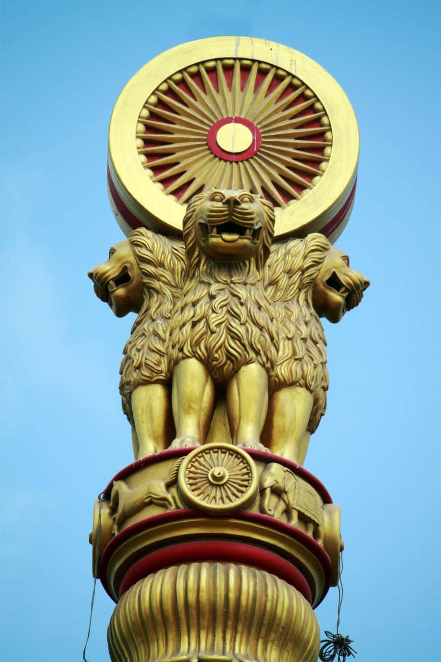 獅子 桌布 壁紙 — 金色四獅雕像立於阿育王柱頂，紅色法輪襯托清澈藍天。
