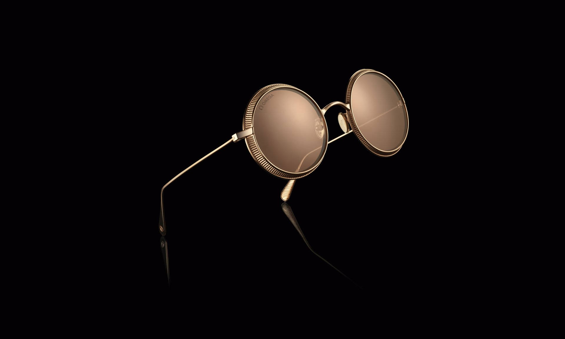 Sunglasses 桌布 壁紙 — 金色圓形太陽眼鏡配反光鏡片，在戲劇性的攝影棚燈光下，放置於黑色反光表面上。