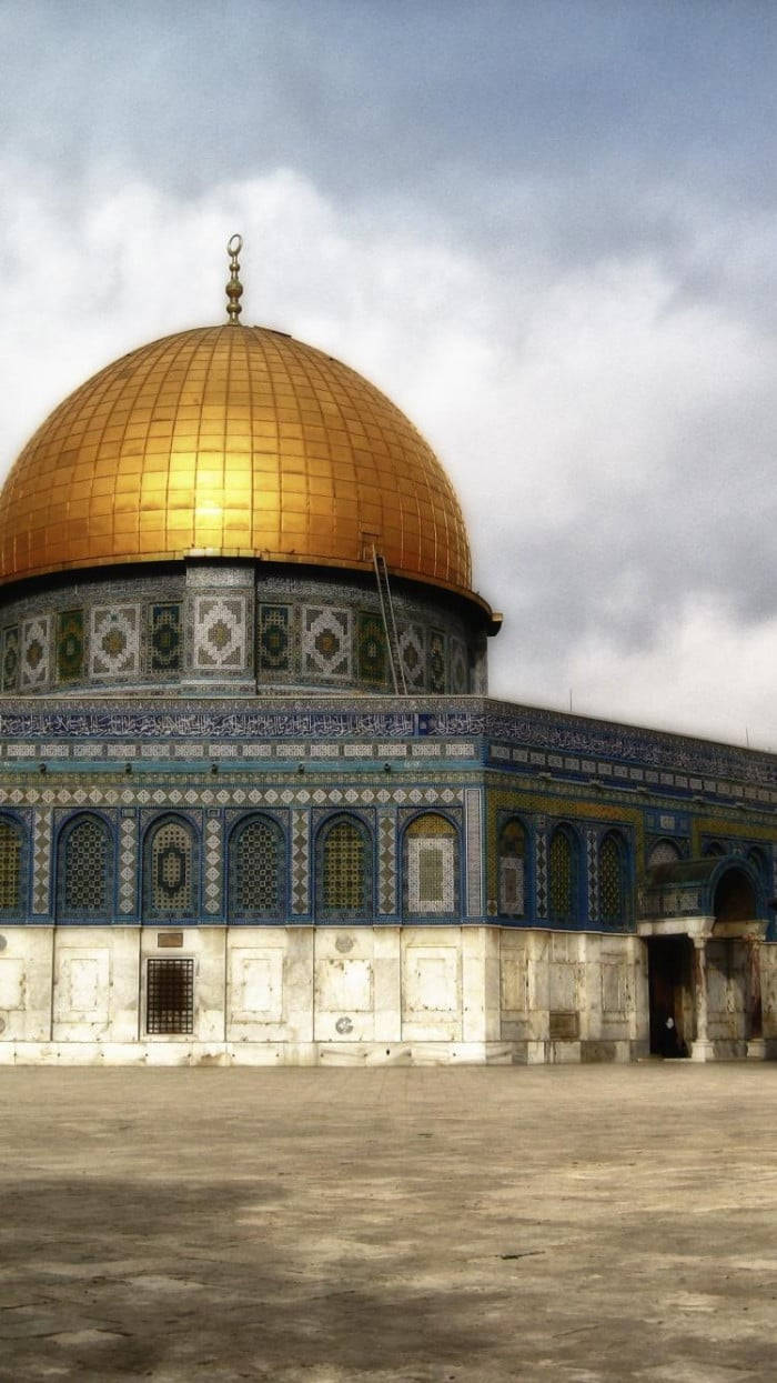 muslim 桌布 壁紙 — 金色圓頂岩石在陰天天空下閃耀，下方有精緻的藍色瓷磚和石拱門。