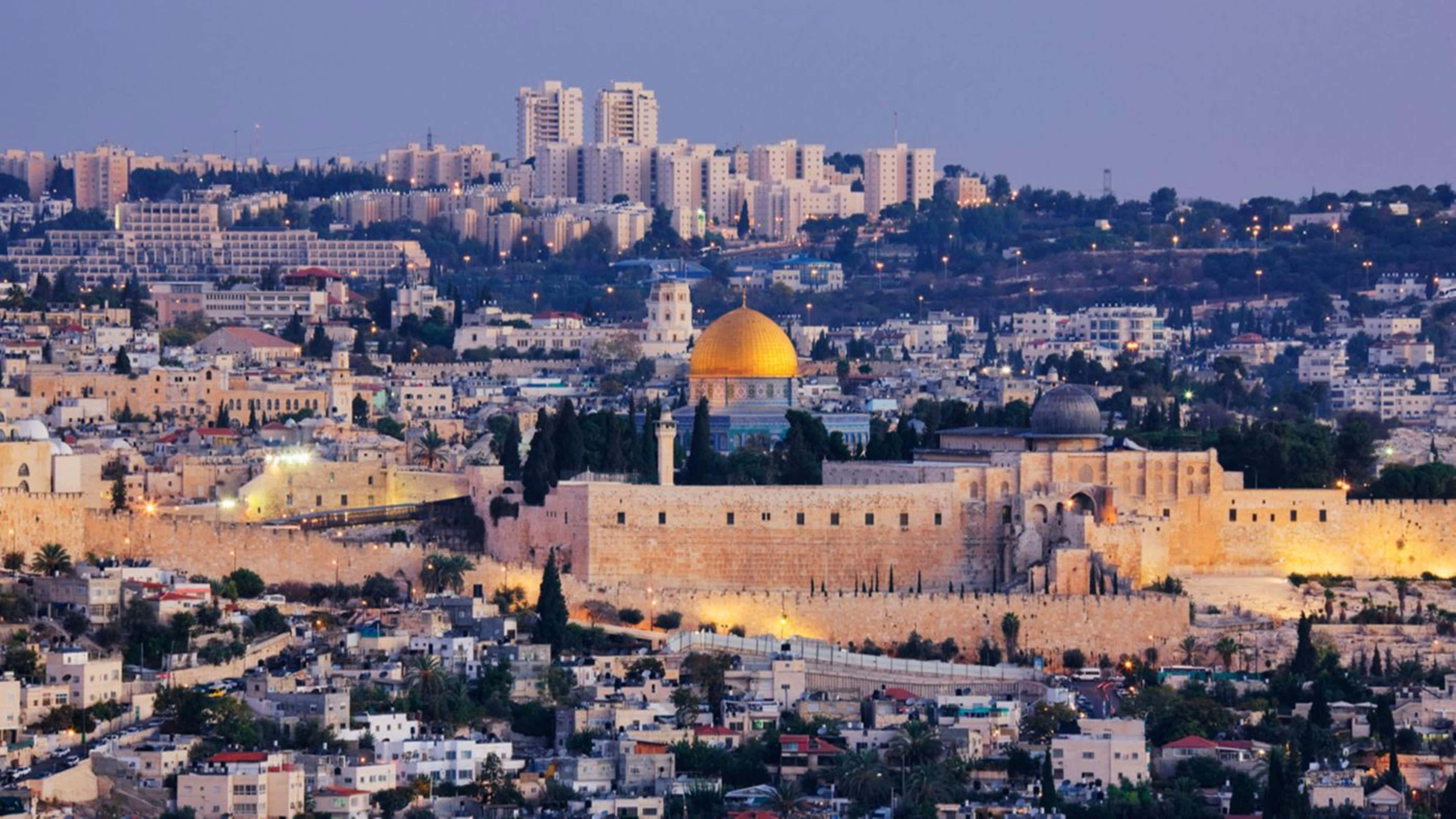 Israel 桌布 壁紙 — 金色圓頂岩石寺在古老石牆上溫暖地發光，城市燈光在耶路撒冷山坡上閃爍於黃昏時分。
