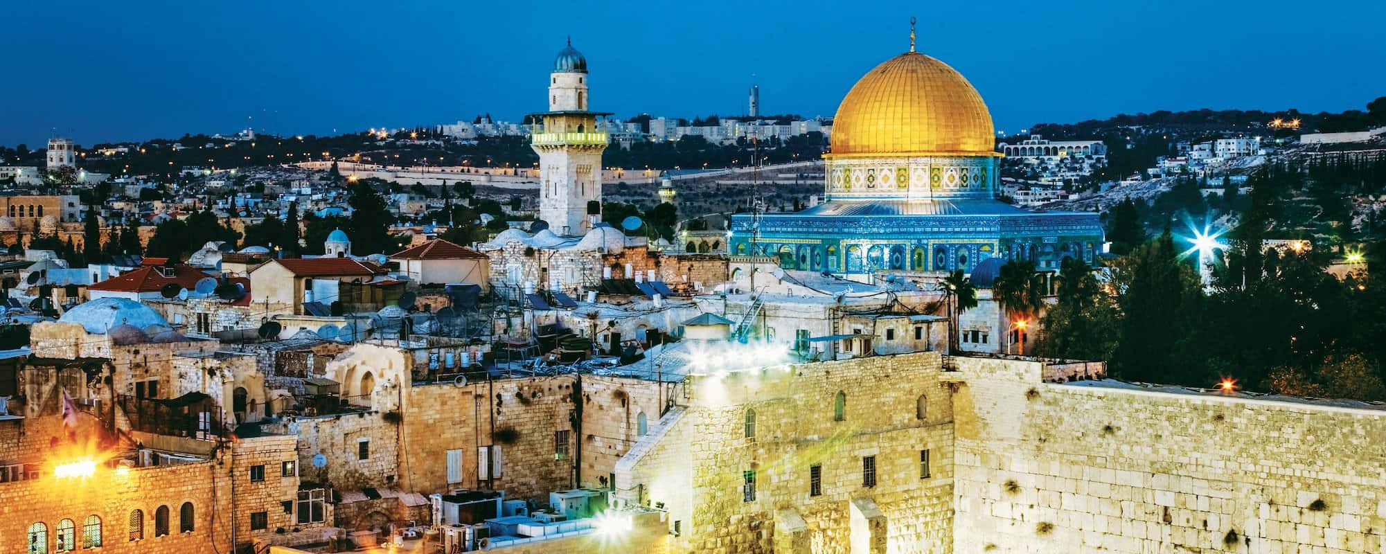 Holy Land 桌布 壁紙 — 金色圓頂岩石寺在暮色天空中溫暖地發光，下方是古老的石頭城市景觀，有燈光點亮的宣禮塔和歷史城牆。