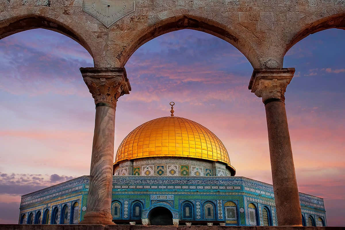 Holy Land 桌布 壁紙 — 金色圓頂清真寺在古老石拱門的映襯下，溫暖地發光，背景是充滿活力的粉紅色和紫色日落天空。