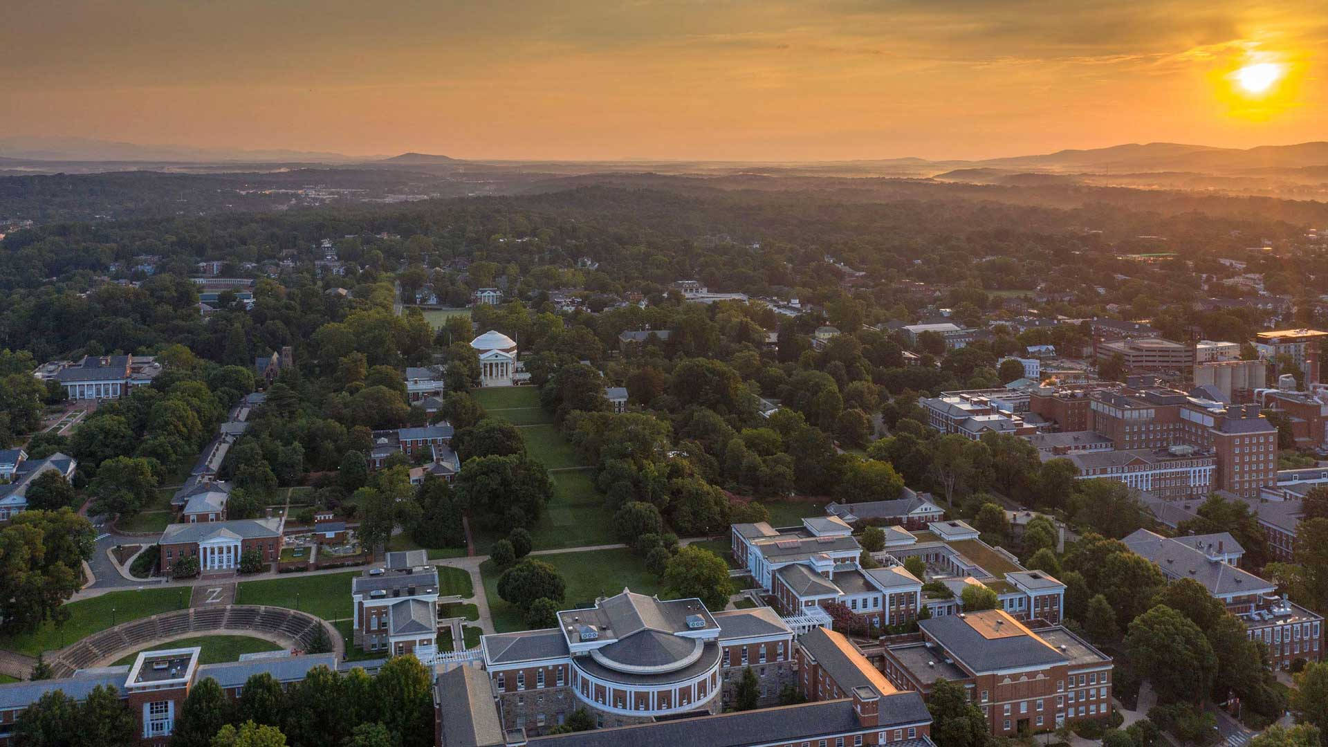 Virginia 桌布 壁紙 — 金色夕陽下的大學校園鳥瞰圖，樹木、建築物和遠山沐浴在溫暖的光線中。