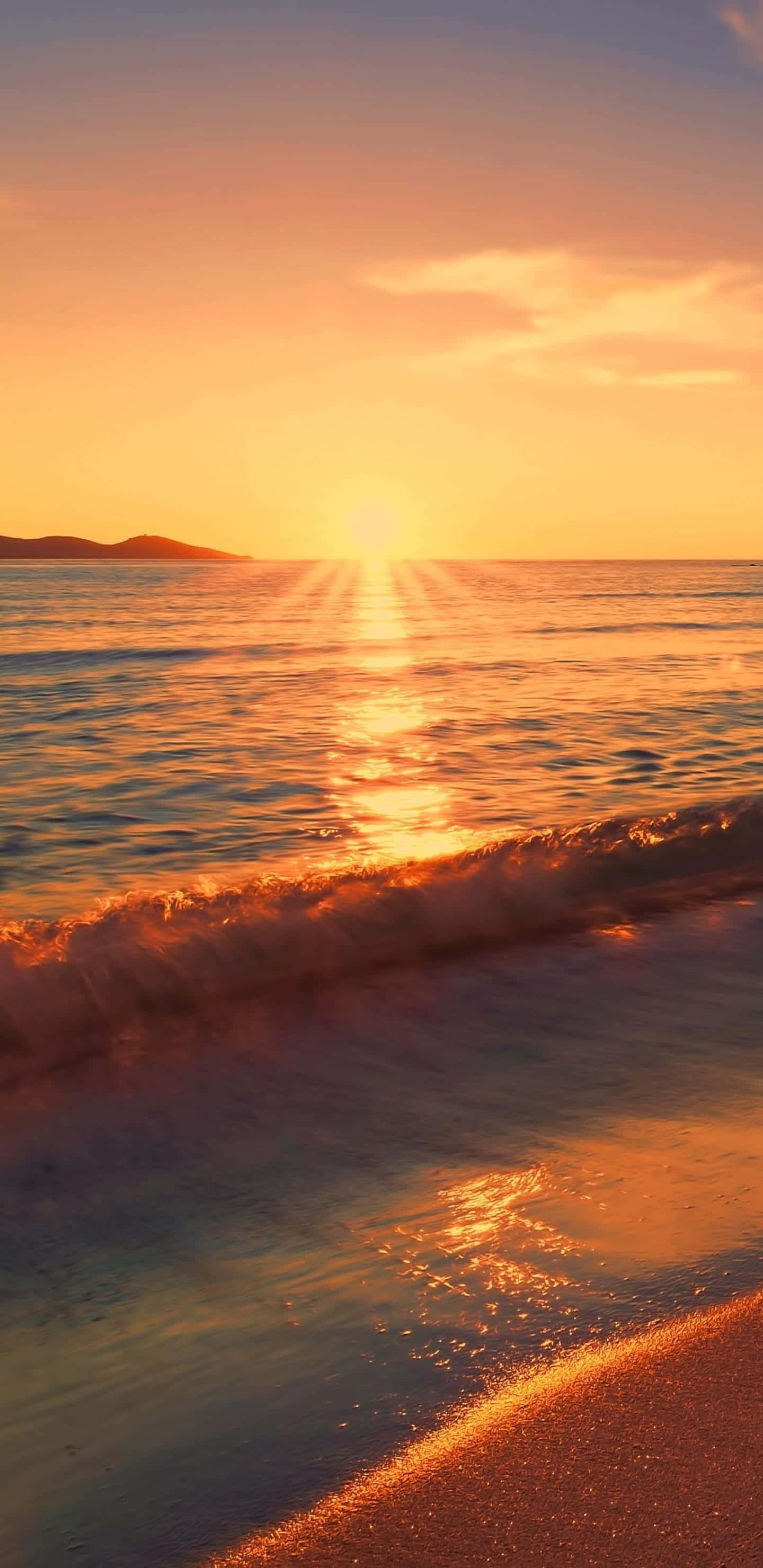 Coastal Sunset 桌布 壁紙 — 金色夕陽在平靜的海面上投射出耀眼的光芒，溫柔的海浪輕吻著沙灘，遠方的山丘呈現出剪影。