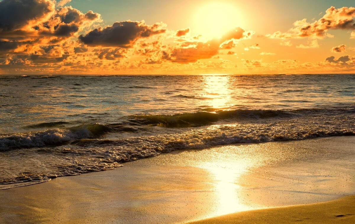 Morning 桌布 壁紙 — 金色夕陽將溫暖光線投射在海洋波浪上，波浪伴隨著散落的雲朵湧上沙灘。