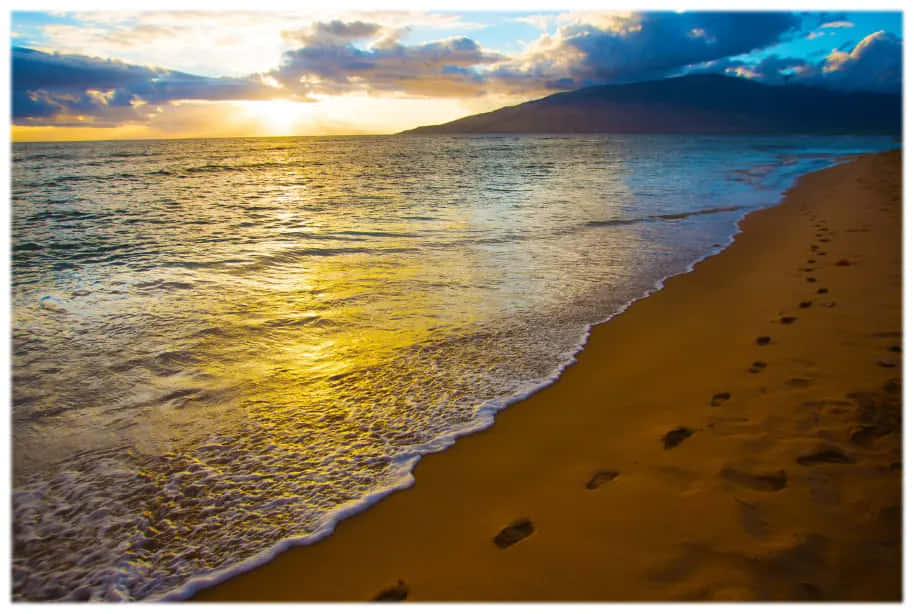 日落 桌布 壁紙 — 金色夕陽將溫暖的光線投射在拍打沙灘的海浪上，沙灘上的腳印通往遠山。