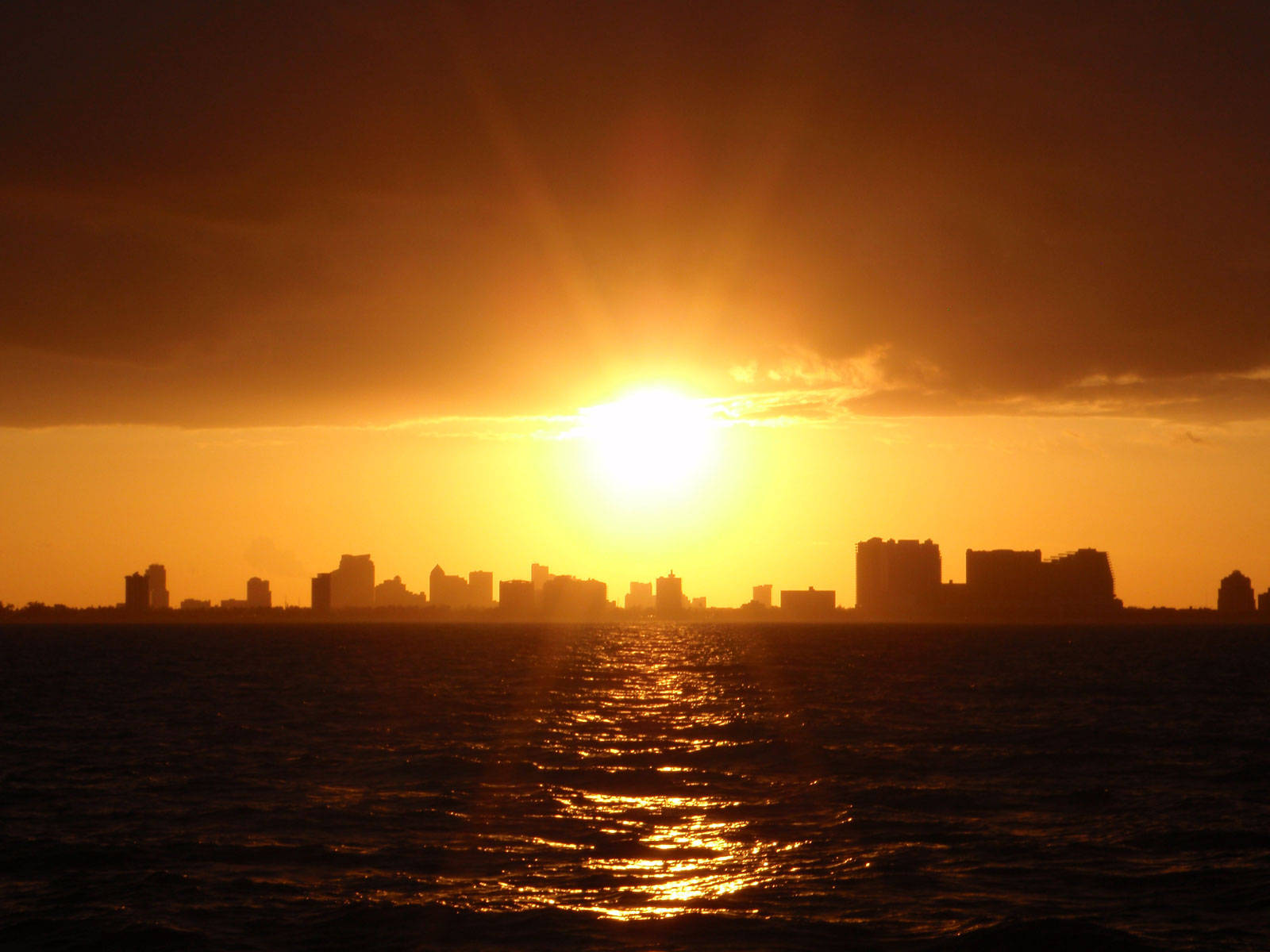 Miami 桌布 壁紙 — 金色夕陽將耀眼的光芒投射在漣漪水面上倒映的城市天際線。