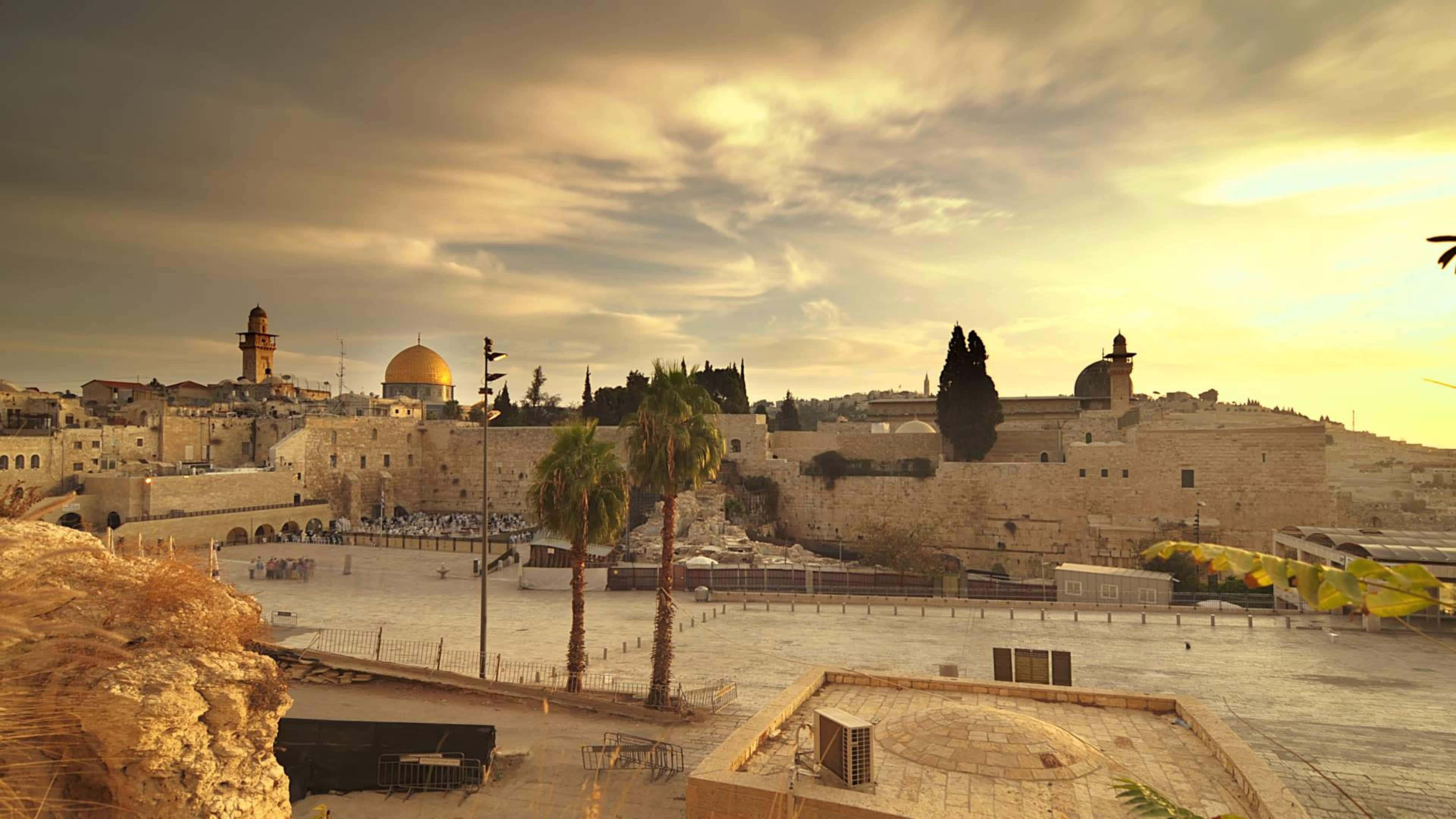 Israel 桌布 壁紙 — 金色夕陽將耶路撒冷歷史天際線上的古老石牆和圓頂清真寺沐浴在溫暖的光芒中。