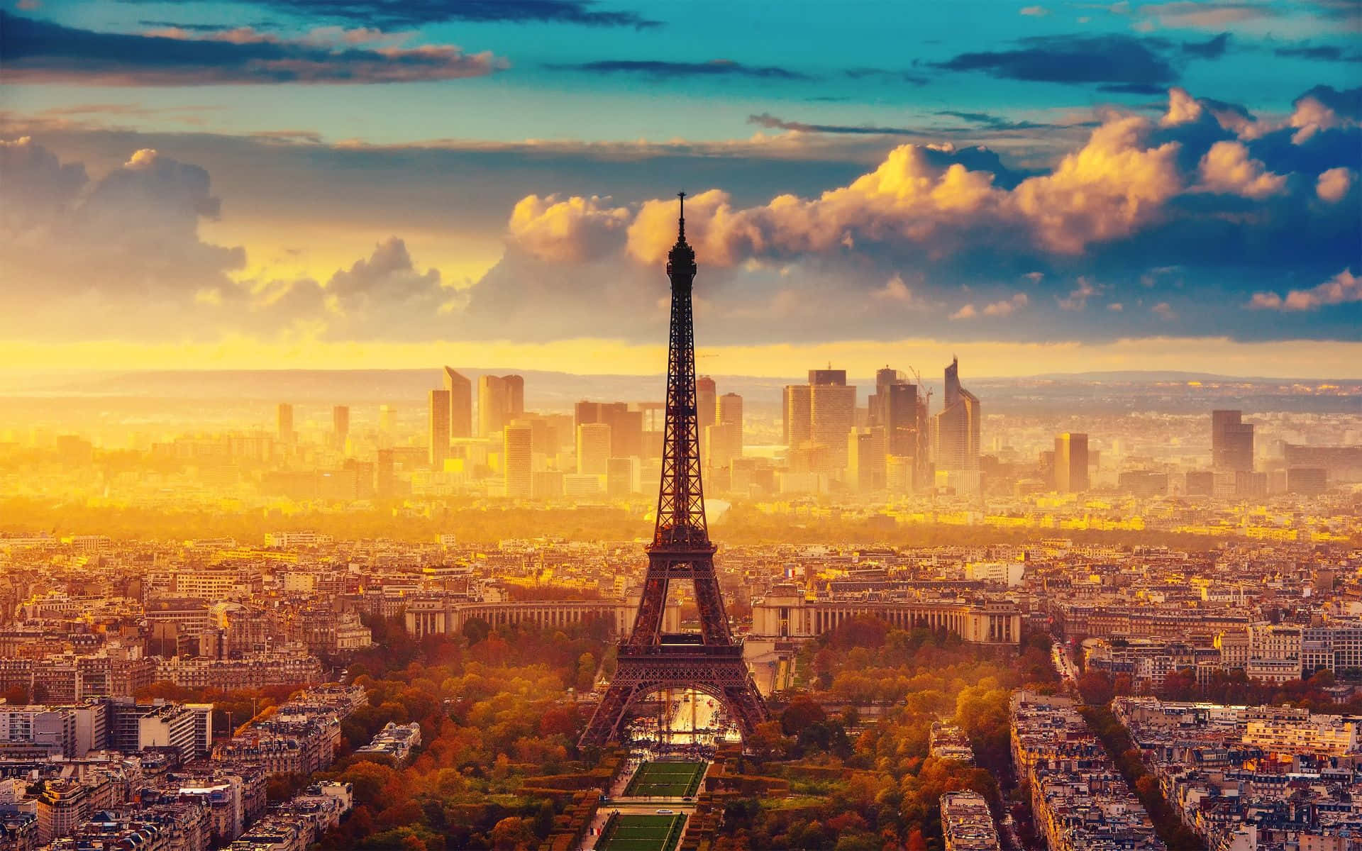 Paris Desktop 桌布 壁紙 — 金色夕陽沐浴在艾菲爾鐵塔和巴黎天際線，在戲劇性的雲層下散發溫暖光芒。