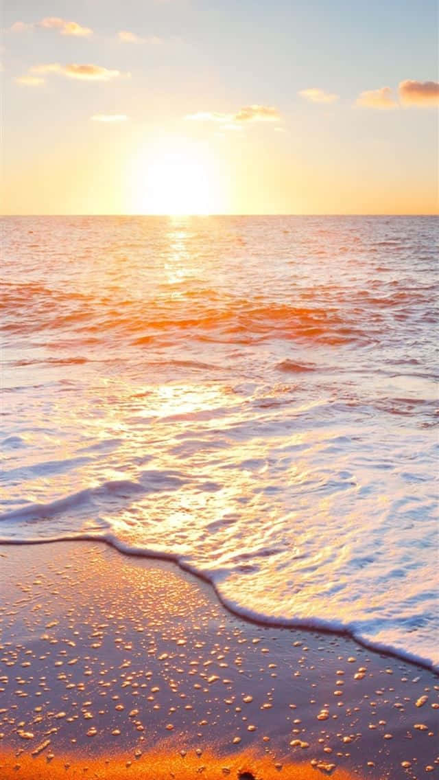 Sunrise iPhone 桌布 壁紙 — 金色夕陽海浪輕輕拍打濕沙，天空柔和粉彩，雲朵散落。
