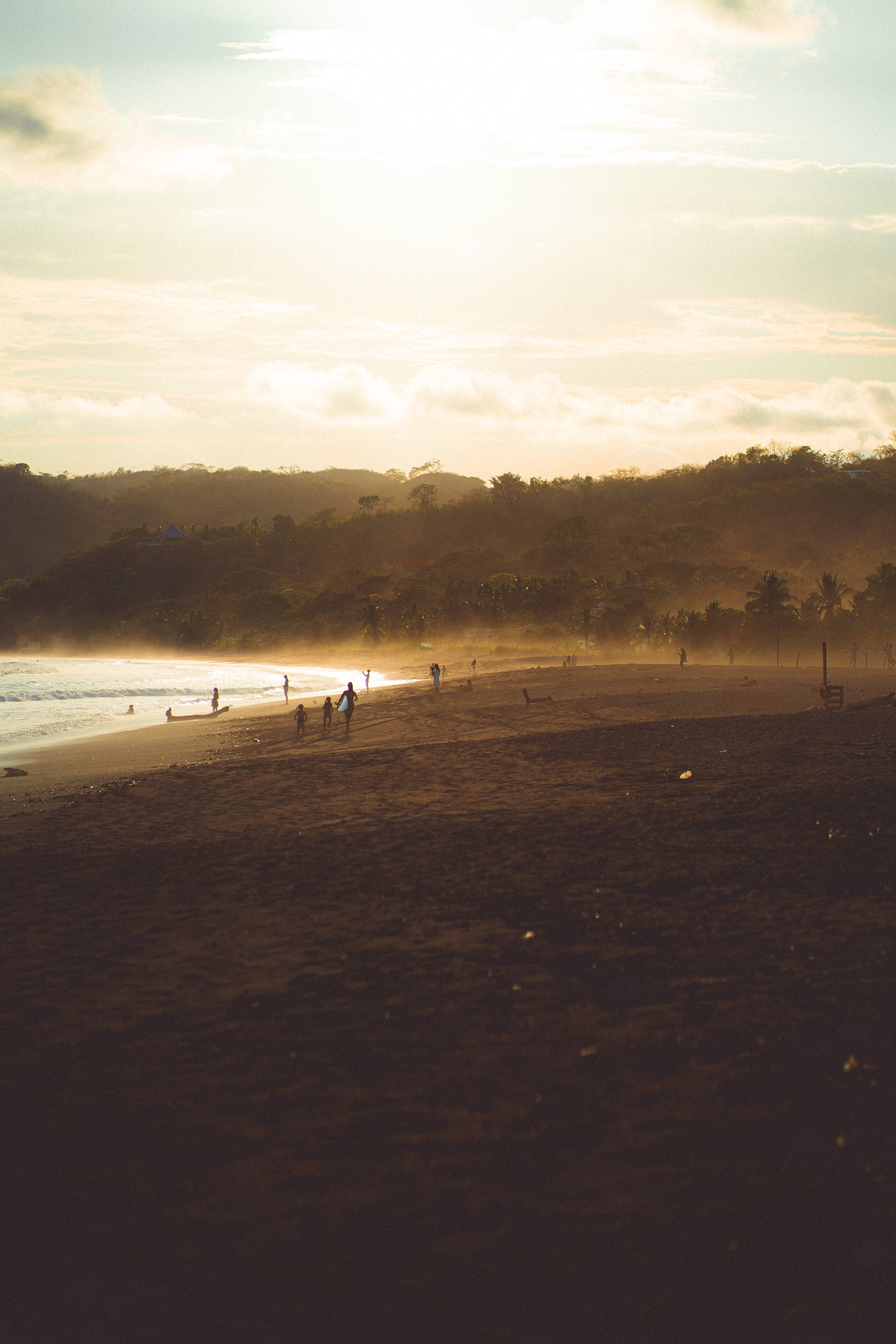 Panama 桌布 壁紙 — 金色夕陽灑落在寧靜的海灘上，剪影般的人們沿著海岸線漫步，溫柔的波浪輕拍著深色的沙灘。