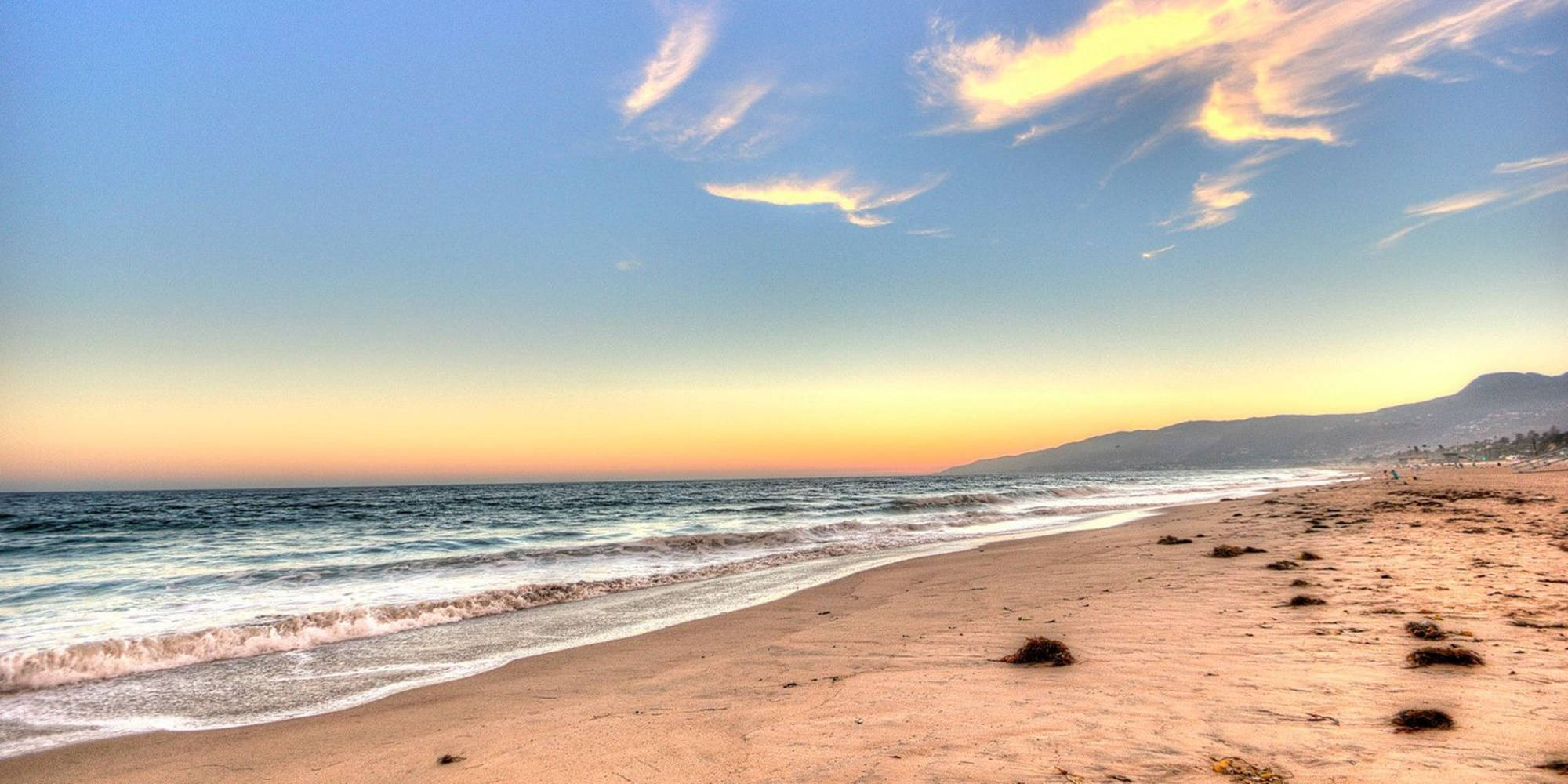 Malibu California 桌布 壁紙 — 金色夕陽為寧靜海灘的天空塗上色彩，溫柔的海浪輕拍沙灘。