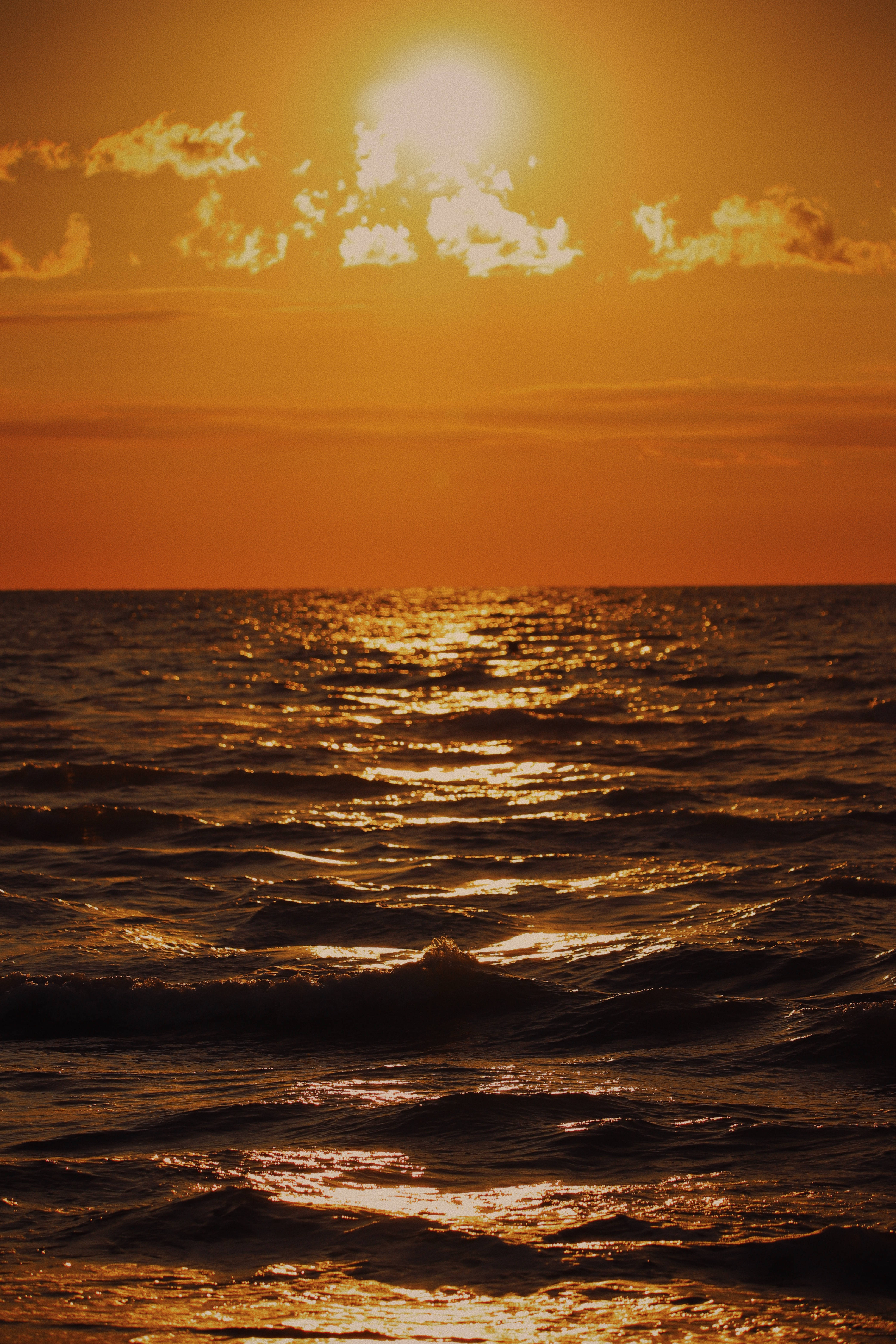 淺棕色 桌布 壁紙 — 金色夕陽落在海洋波浪上，在溫暖的橙色天空下，將閃爍的光芒投射在紋理水面上。
