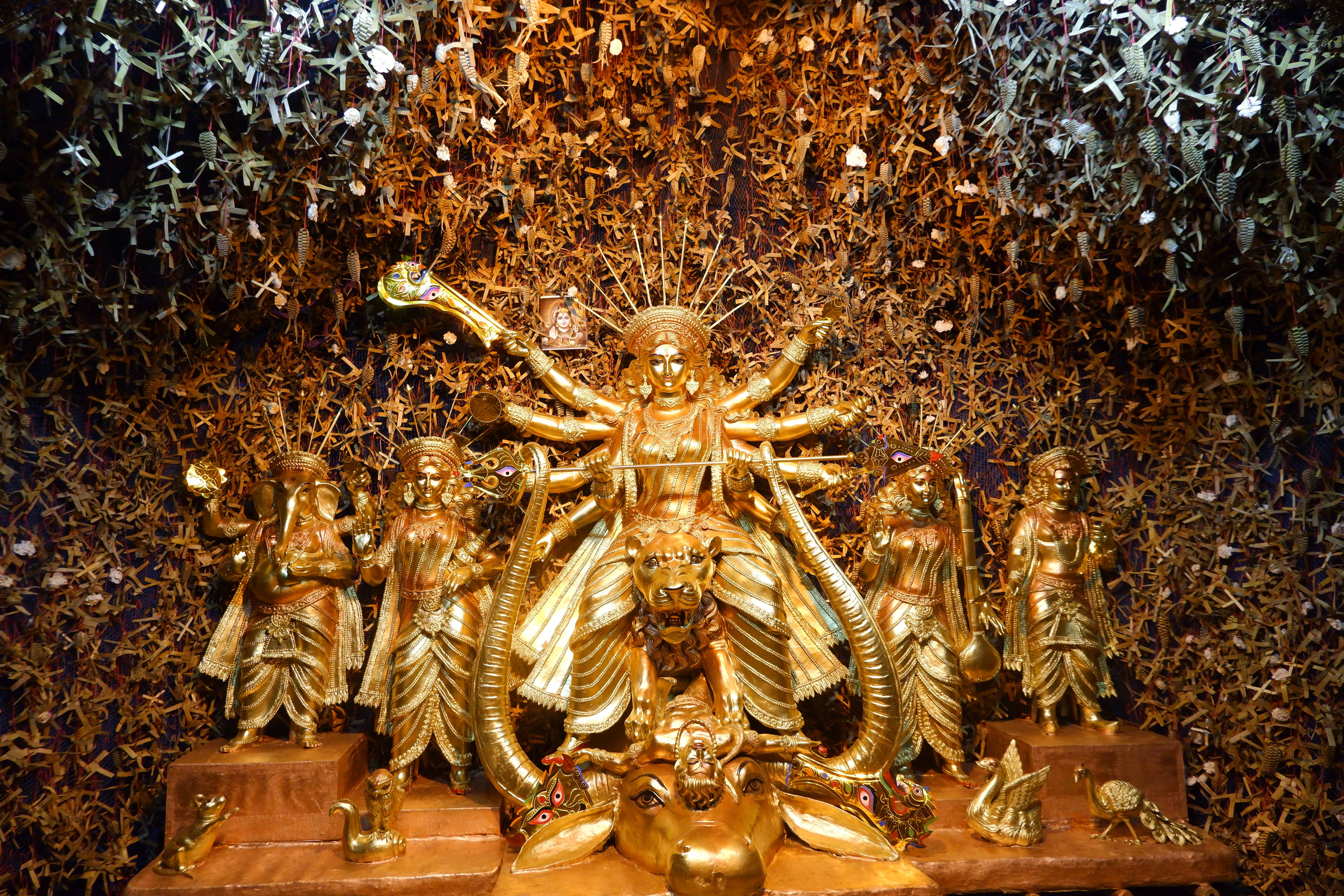 Durga 桌布 壁紙 — 金色多臂多武器杜爾迦雕像，周圍環繞著金色和銀色摺紙鶴。