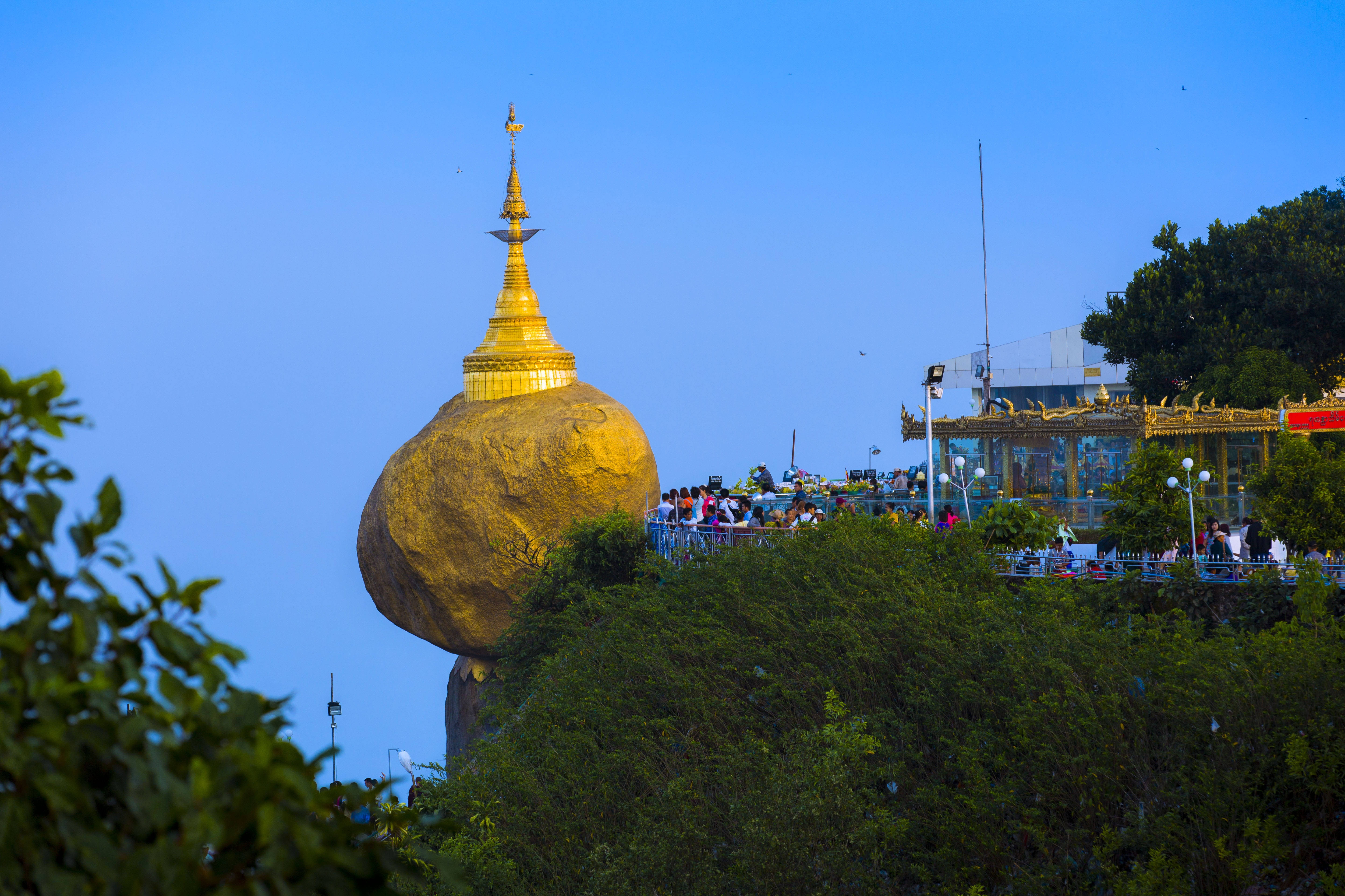 Yangon 桌布 壁紙 — 金色寶塔冠在一塊巨大岩石上，岩石坐落於翠綠山丘之巔，天空湛藍清澈。