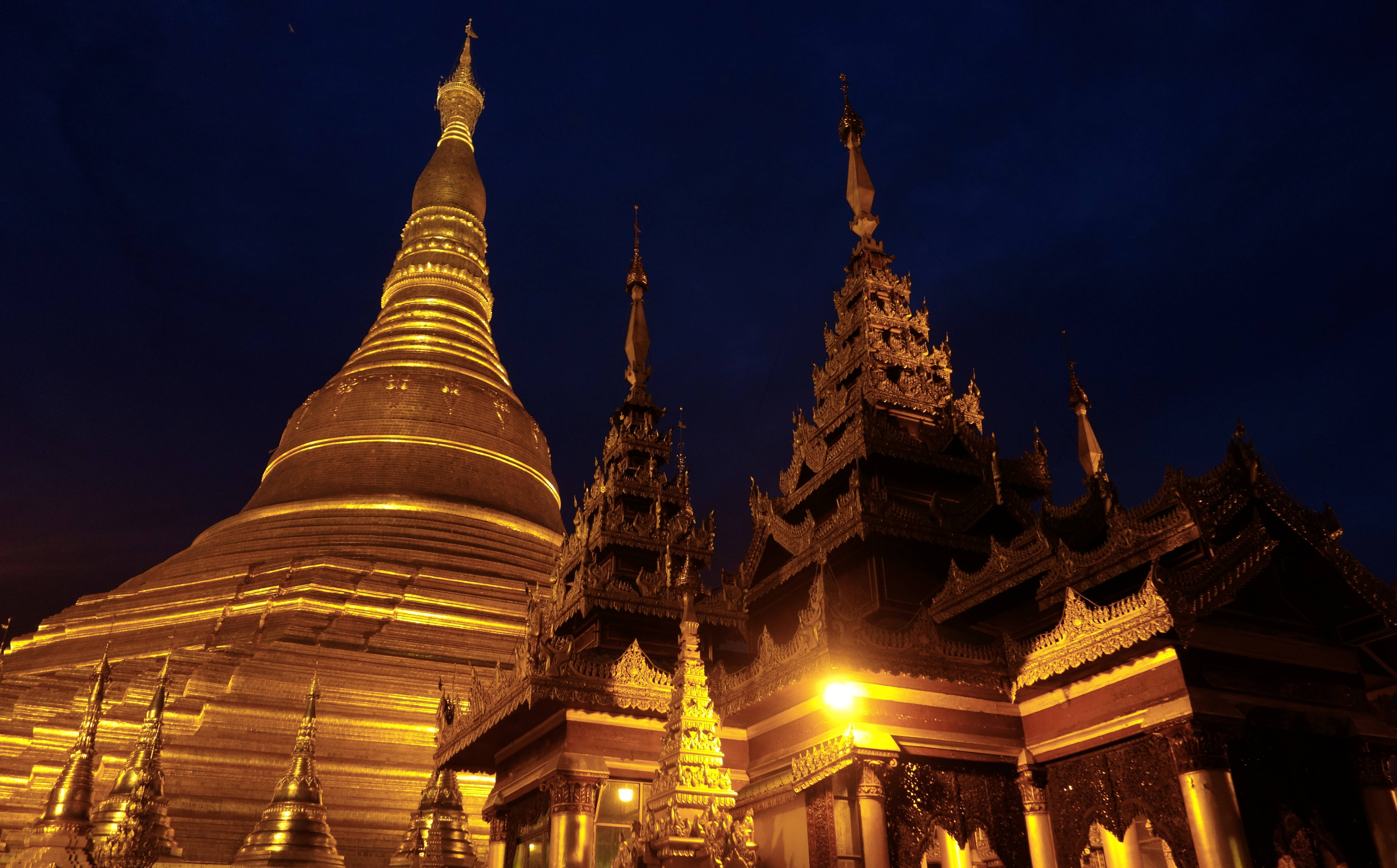 Yangon 桌布 壁紙 — 金色寶塔和華麗的寺廟建築在深藍色的夜空中溫暖地發光。