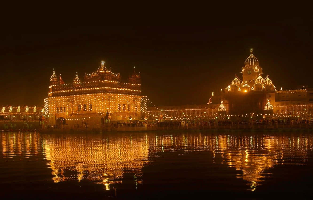 Golden Temple 桌布 壁紙 — 金色寺廟在夜間被溫暖的燈光照亮，美麗地倒映在平靜的水面上。