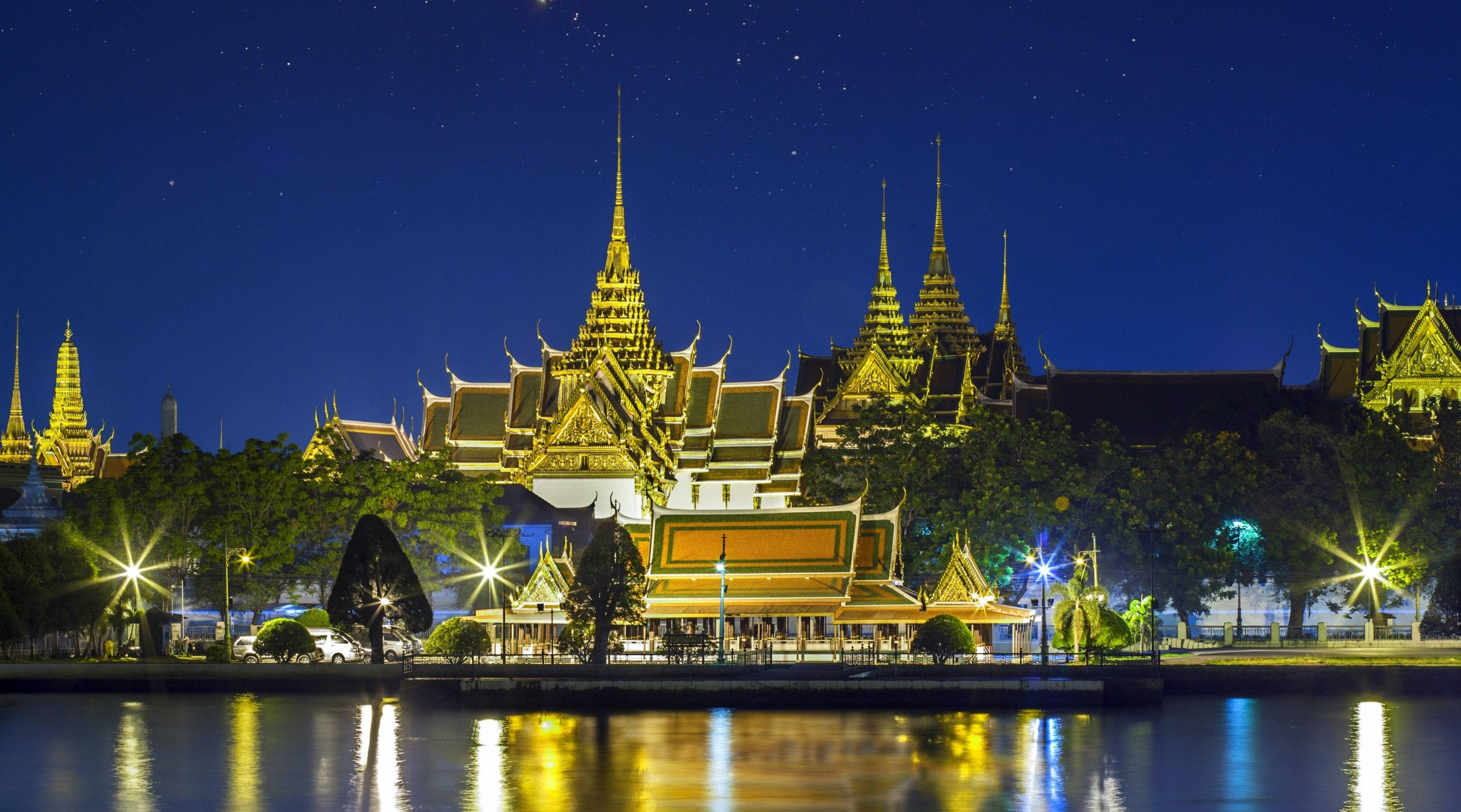 Bangkok 桌布 壁紙 — 金色寺廟尖塔在星空下閃耀，倒映在平靜的河水之中。