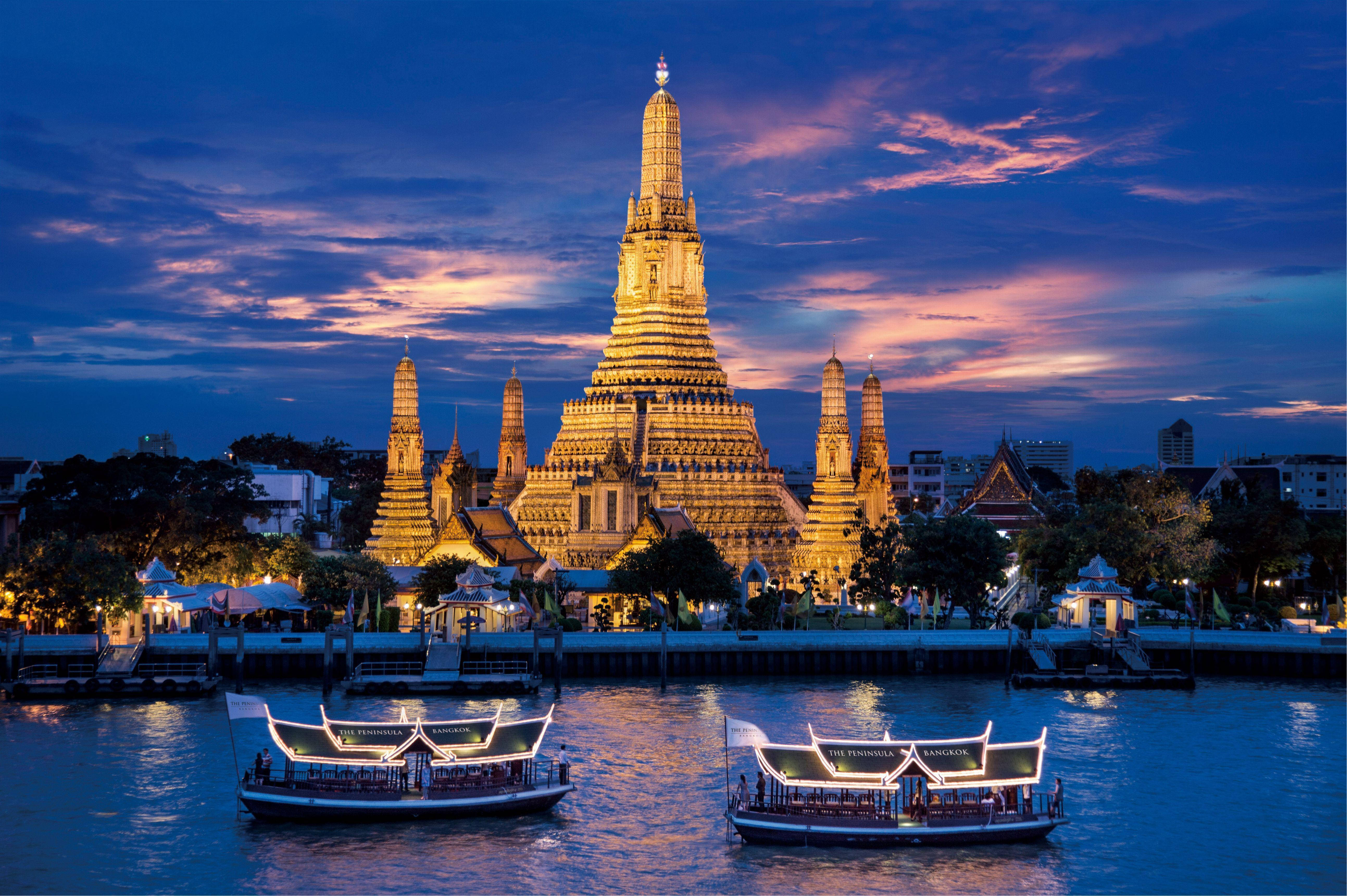 Bangkok 桌布 壁紙 — 金色寺廟尖頂在暮色天空中閃耀，河船在鮮豔的粉紅和藍色雲彩下滑行。