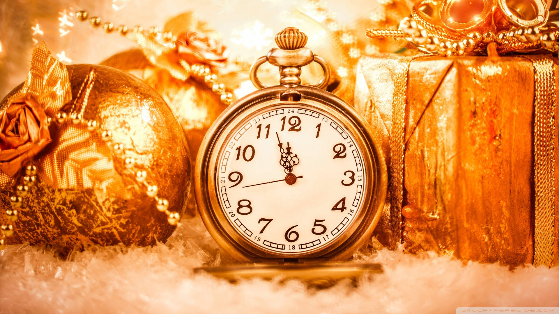 Time 桌布 壁紙 — 金色懷錶放在雪地上，旁邊有包裝好的禮物和裝飾品，在節日燈光下溫暖地閃耀。