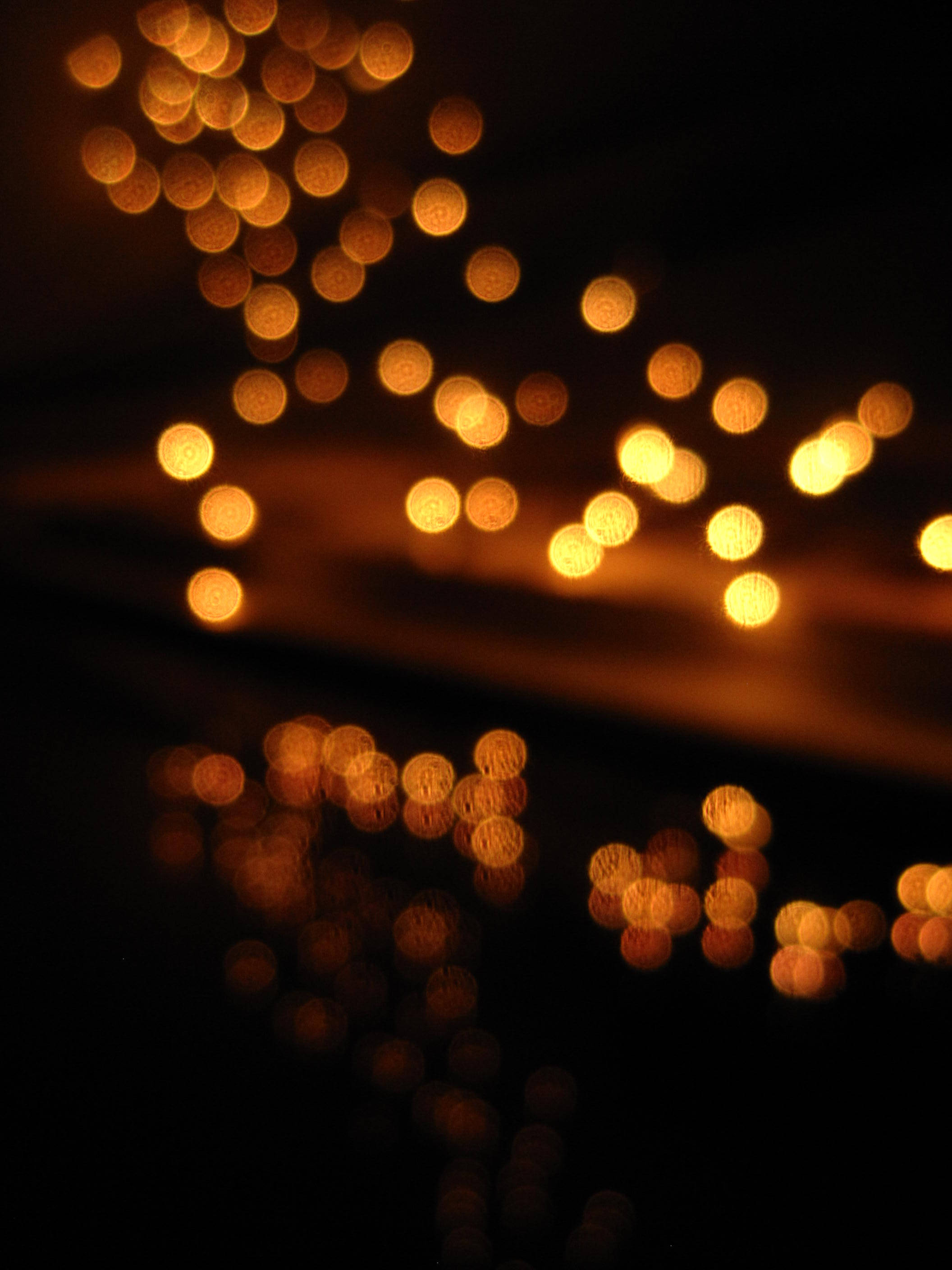 Bokeh 桌布 壁紙 — 金色散景燈光在深色背景上柔和閃爍，下方有微妙的倒影。