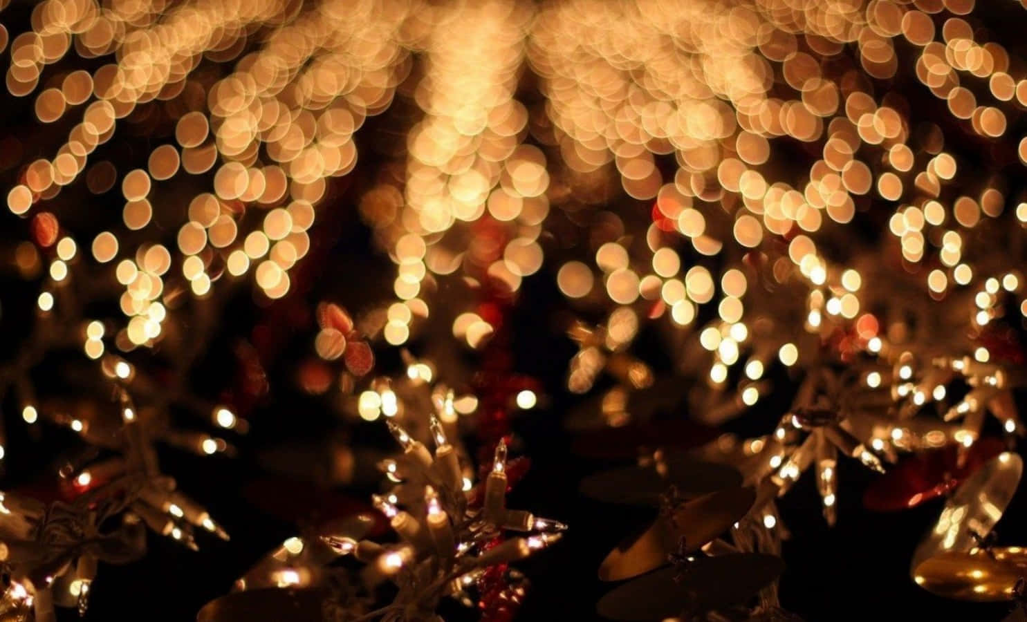 Tumblr Christmas 桌布 壁紙 — 金色散景燈光在黑暗背景下閃爍，前景有節日紅色裝飾品和金屬星星裝飾。