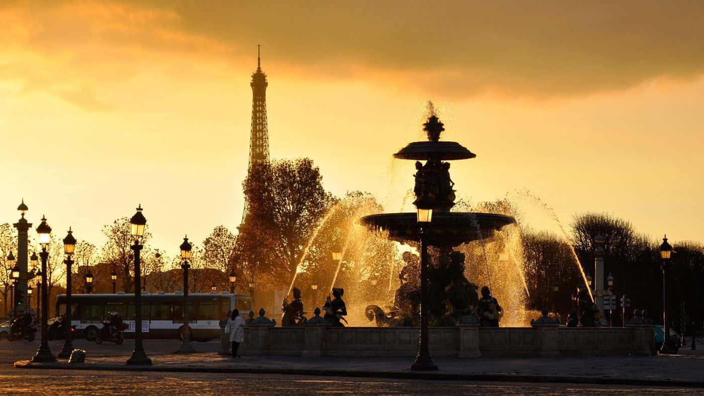 Paris Desktop 桌布 壁紙 — 金色日落勾勒出巴黎艾菲爾鐵塔和一個大型噴泉的輪廓，附近有散步的人們。
