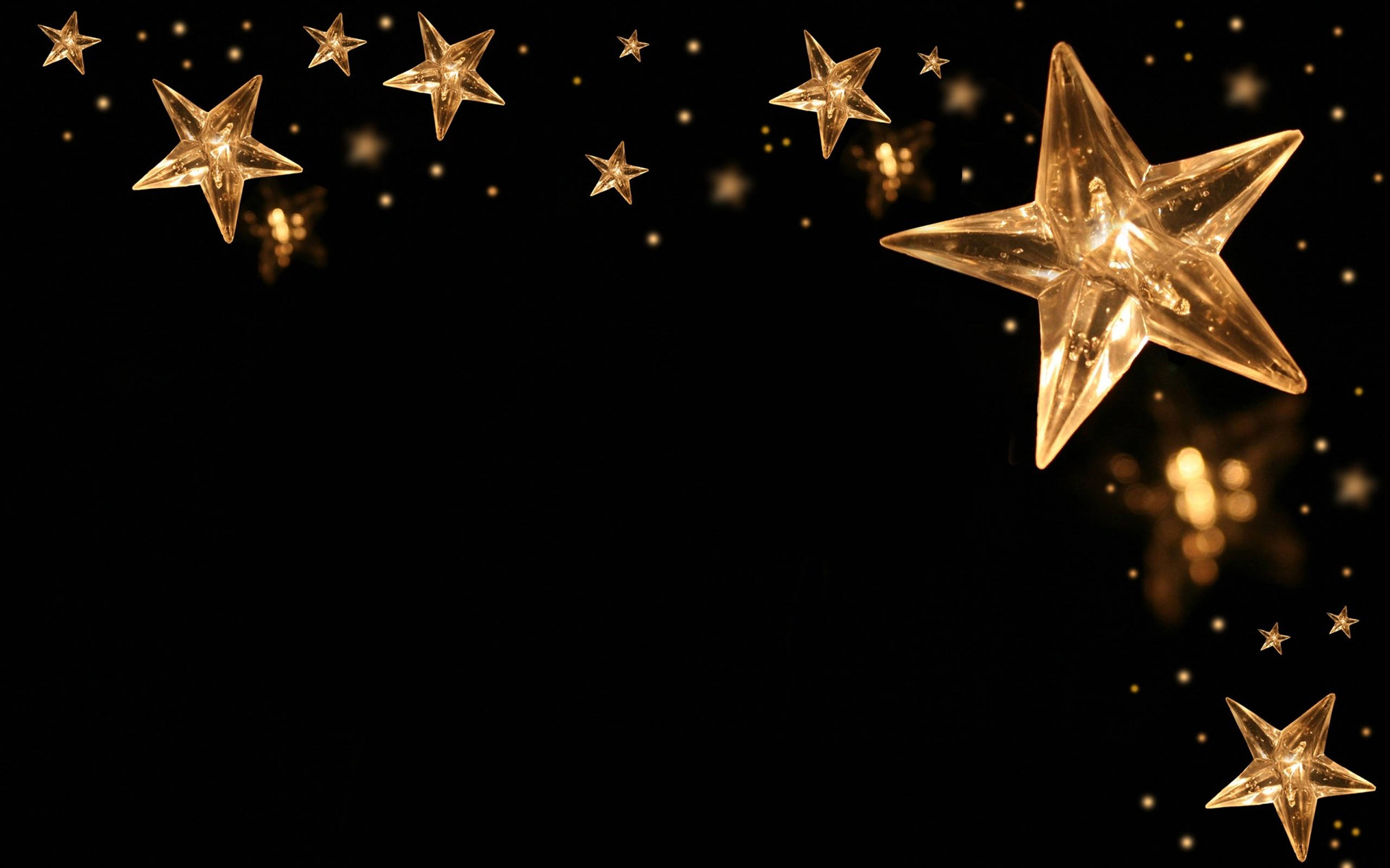 Stars 桌布 壁紙 — 金色星形燈光在深黑色背景上溫暖地發光，帶有柔和的散景閃爍效果。