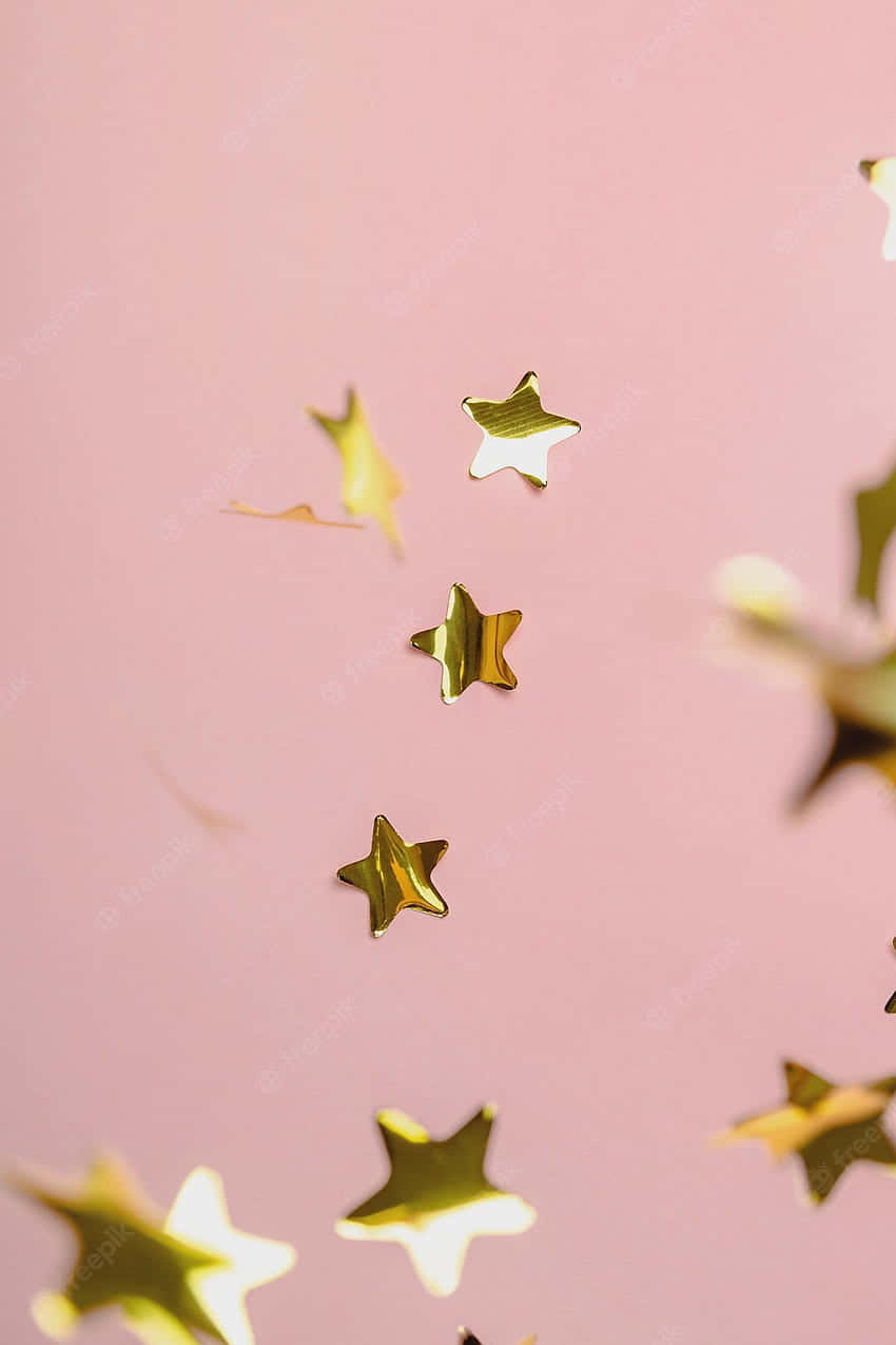 Light Pink And Gold 桌布 壁紙 — 金色星形紙屑在柔和的粉紅色背景上以淺景深漂浮和散落。