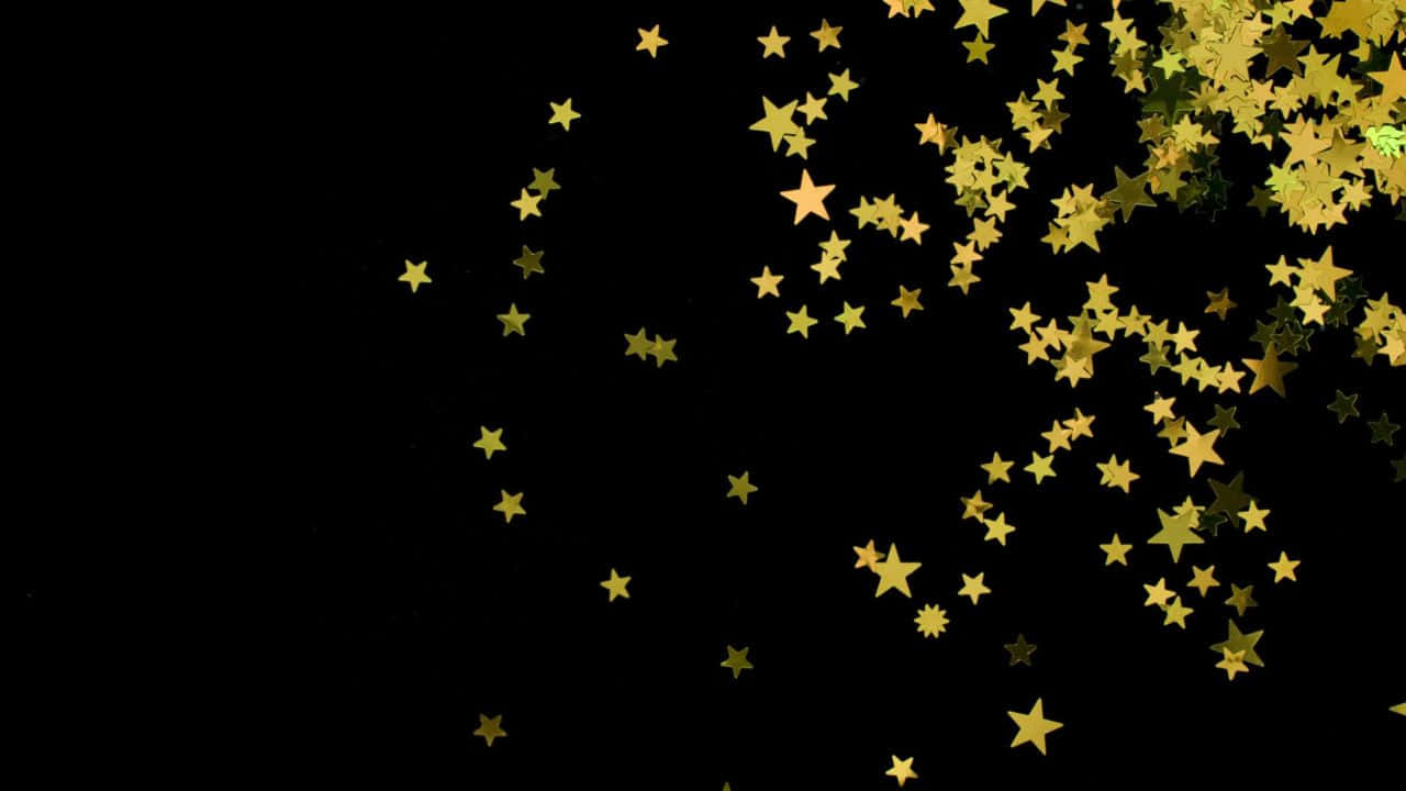 High Resolution Black And Gold 桌布 壁紙 — 金色星形紙屑在純黑背景上爆開，營造出節慶閃爍效果。