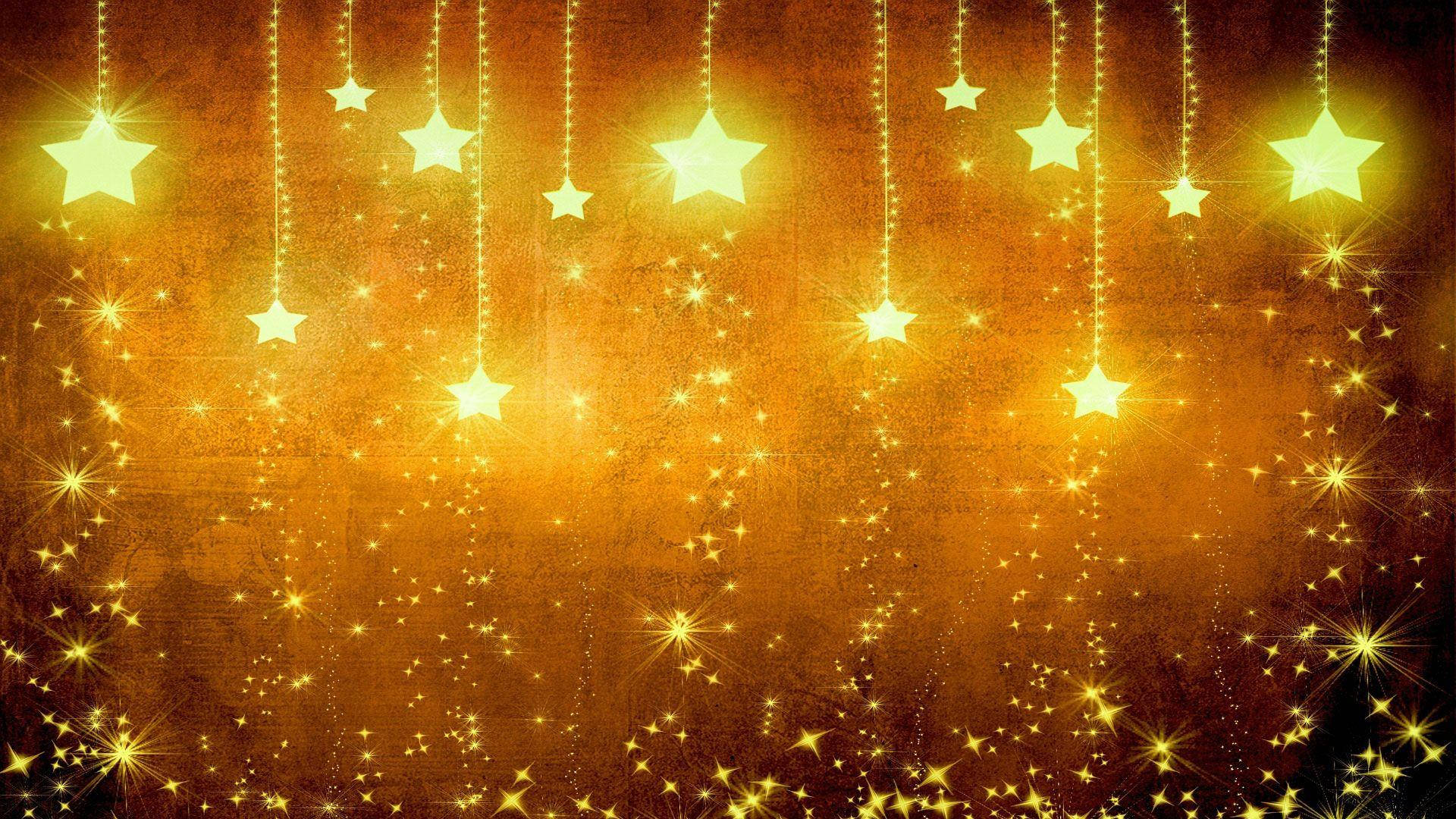 Gold Stars 桌布 壁紙 — 金色星星從發光的繩子上垂下來，懸掛在帶有紋理的琥珀色背景上，閃爍著耀眼的光芒。