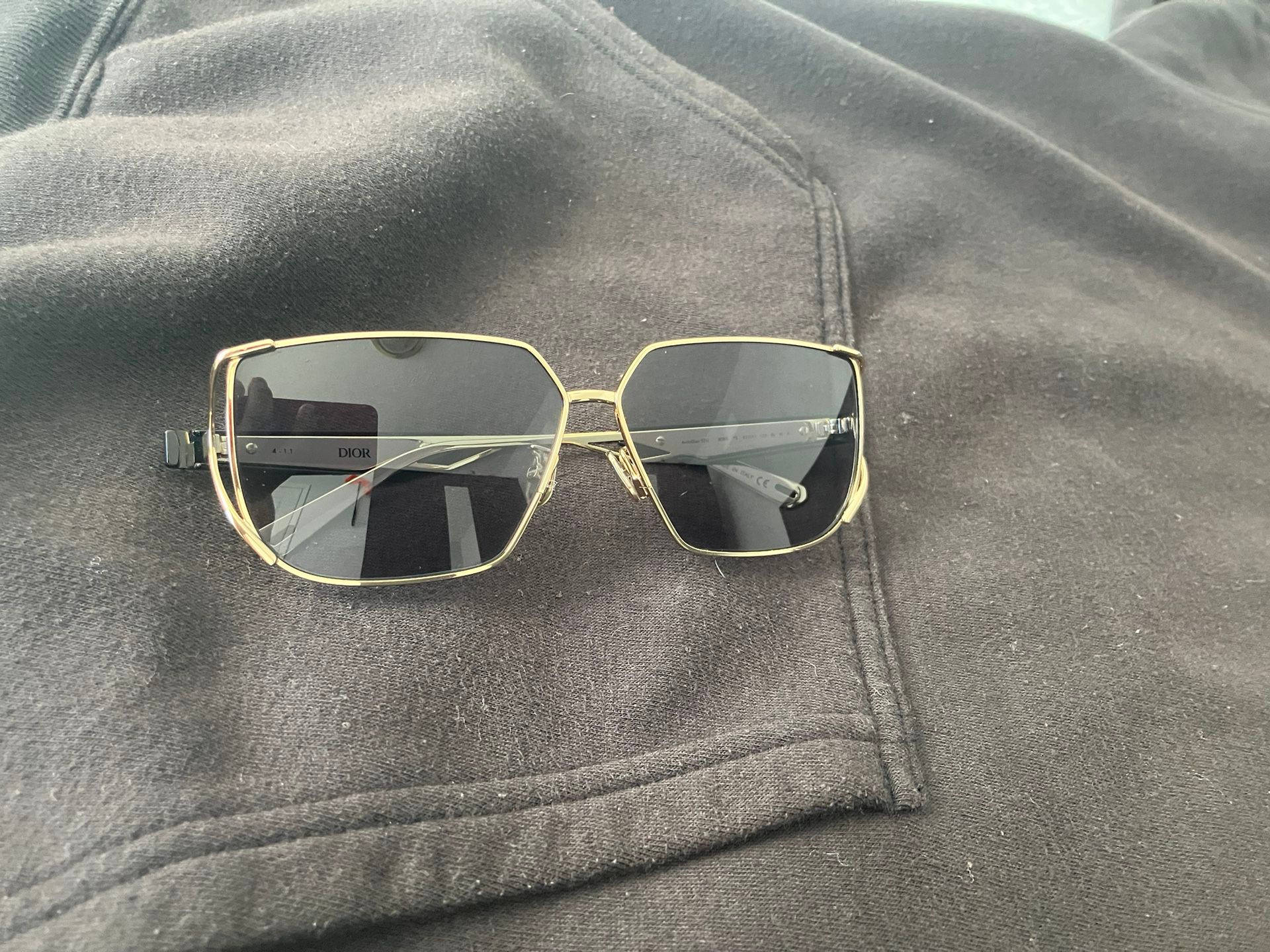 金色框Dior太陽眼鏡放在深灰色連帽衫口袋上。 — Dior 動態 壁紙