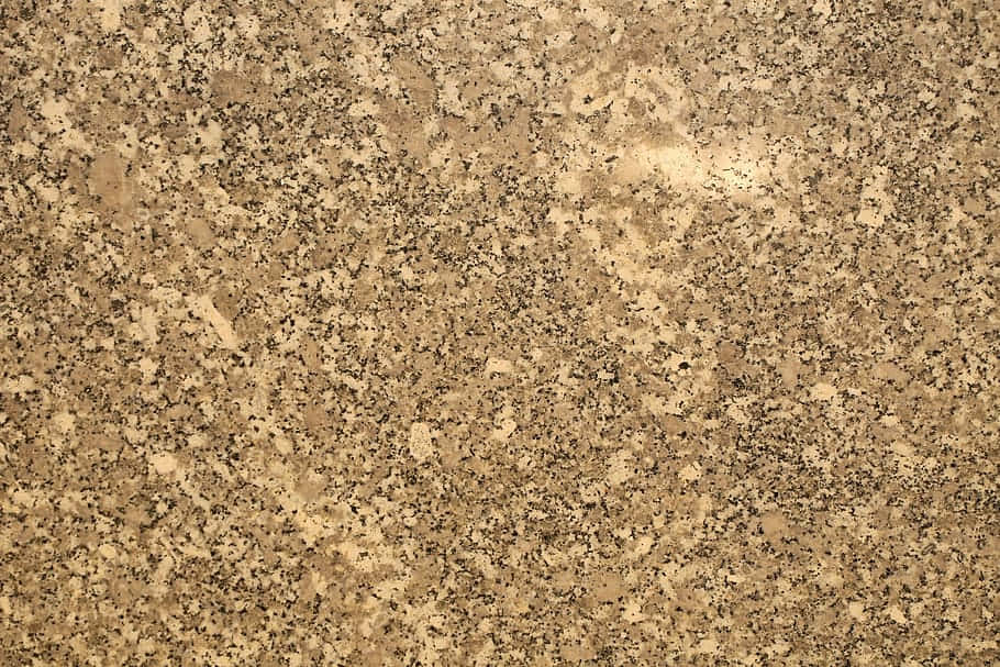 Granite 桌布 壁紙 — 金色棕色花崗岩的特寫，在均勻光線下有黑色和米色斑點礦物顆粒。