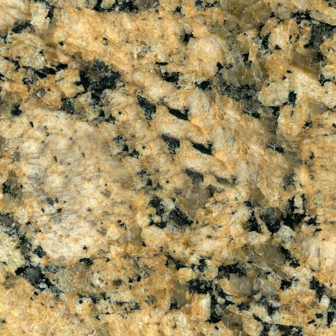 Granite 桌布 壁紙 — 金色棕色花崗岩的特寫，帶有黑色和灰色的礦物斑點，顯示天然結晶質地。