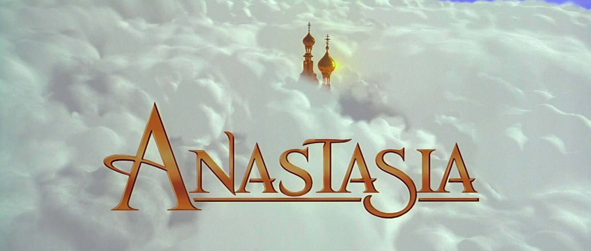Anastasia 桌布 壁紙 — 金色標題 Anastasia 從蓬鬆的雲朵中浮現，洋蔥圓頂大教堂的尖頂在上方隱約可見。