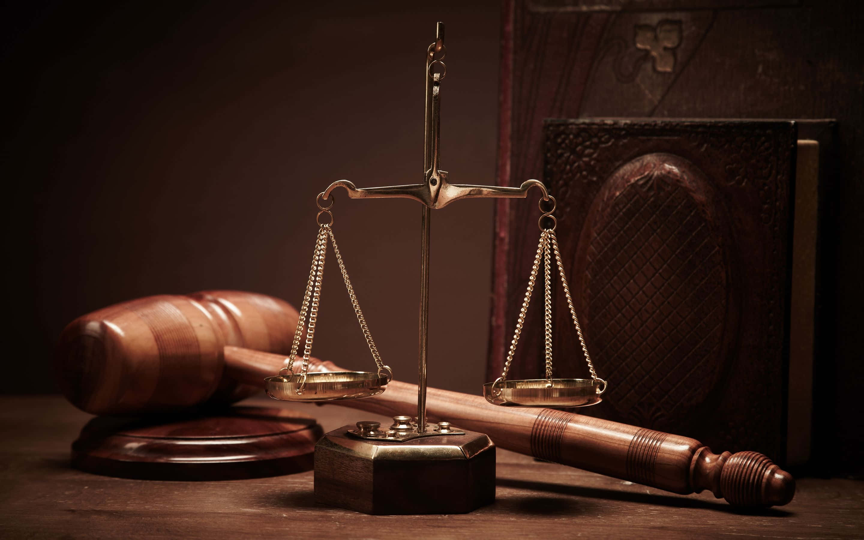 Court 桌布 壁紙 — 金色正義天秤平衡放在木槌和法律書上，處於溫暖昏暗的燈光中。