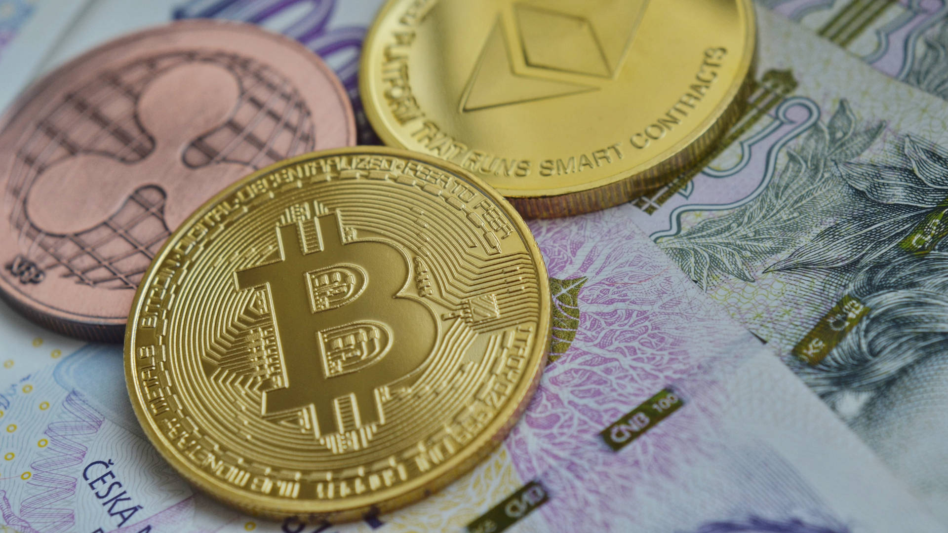 以太坊 桌布 壁紙 — 金色比特幣、以太幣和萊特幣硬幣放在捷克克朗紙幣上，構成特寫金融構圖。