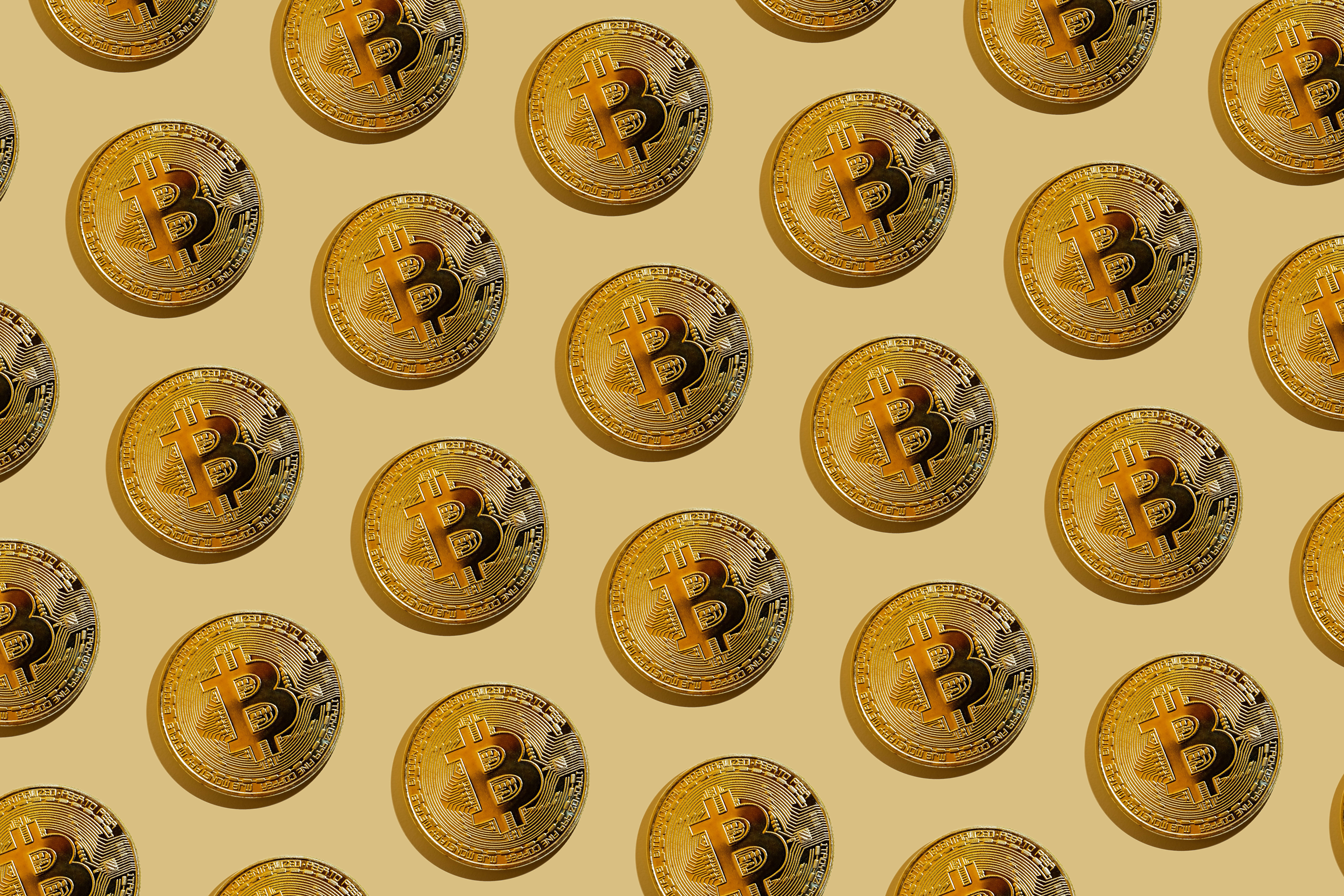 Cryptocurrency 桌布 壁紙 — 金色比特幣硬幣以重複圖案排列在溫暖的米色背景上。