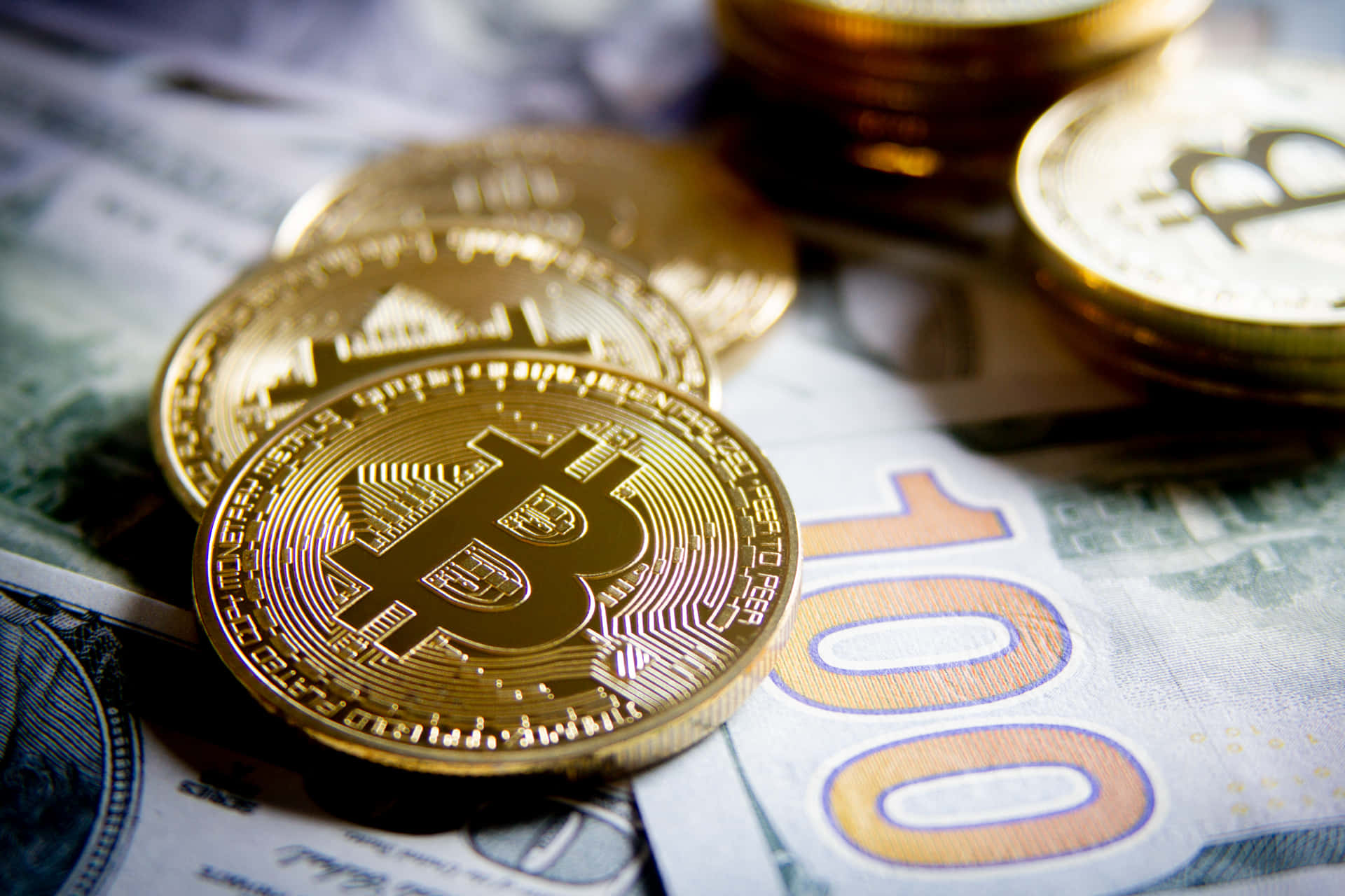 比特幣 桌布 壁紙 — 金色比特幣硬幣放在一百美元鈔票和歐元鈔票上，特寫金融構圖。