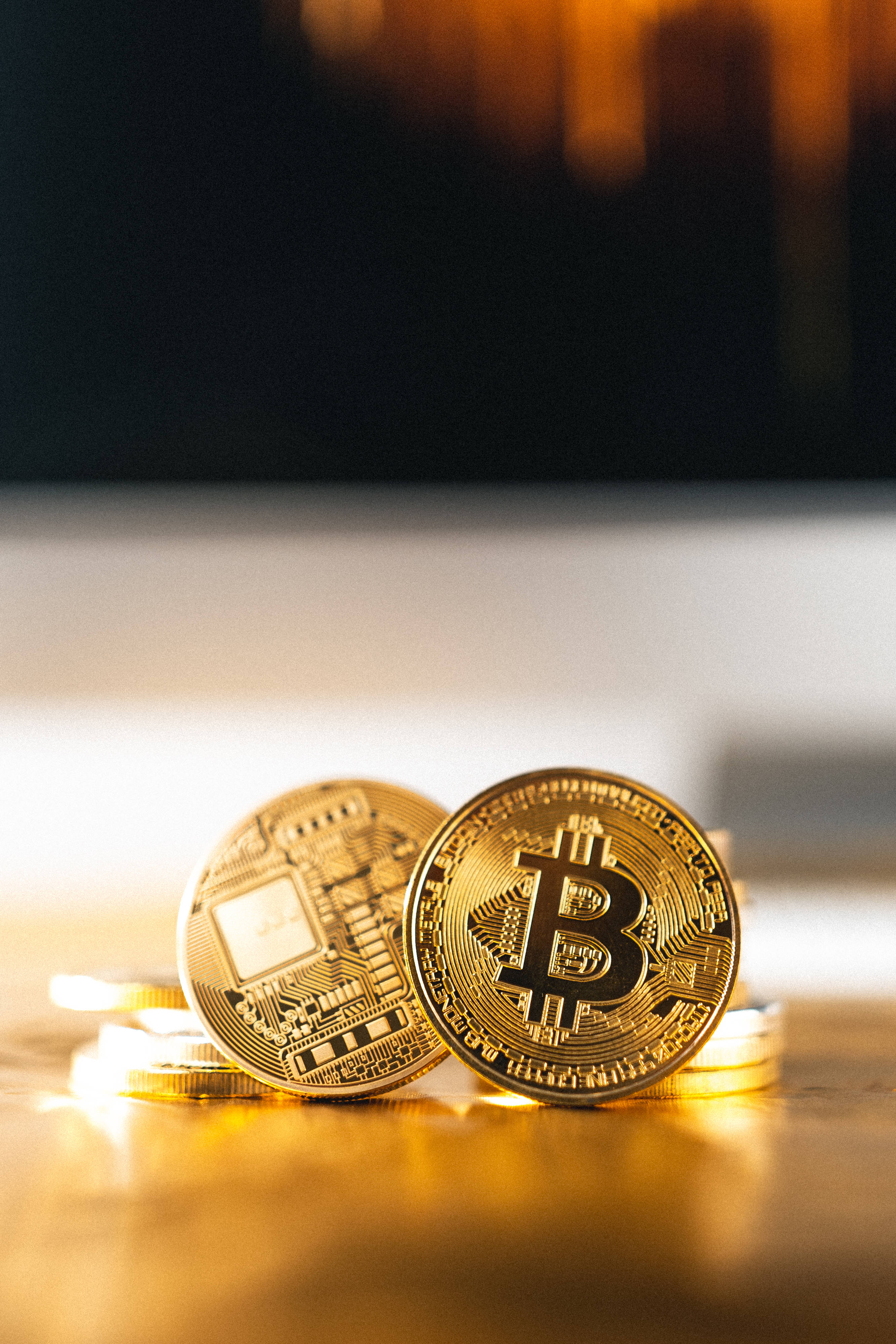 Cryptocurrency 桌布 壁紙 — 金色比特幣硬幣放在木質表面上，帶有溫暖的背光和模糊的背景。