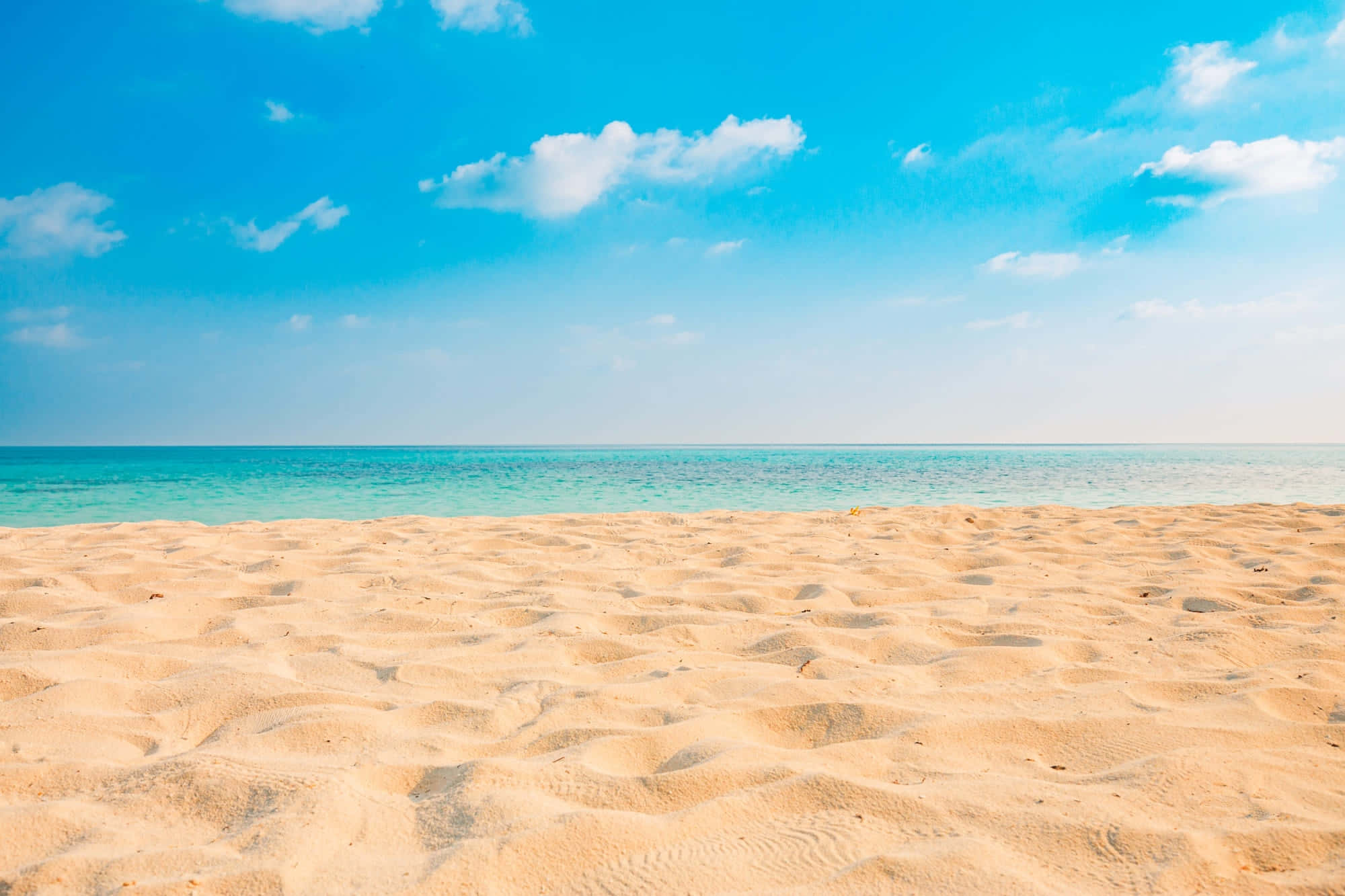 Beach Photography 桌布 壁紙 — 金色沙灘延伸至碧綠海洋，上方是晴朗藍天與蓬鬆白雲。