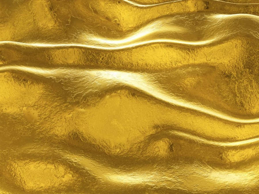 Shiny Gold 桌布 壁紙 — 金色波紋箔紙的特寫，帶有柔和的高光和紋理褶皺，營造出奢華的抽象表面。