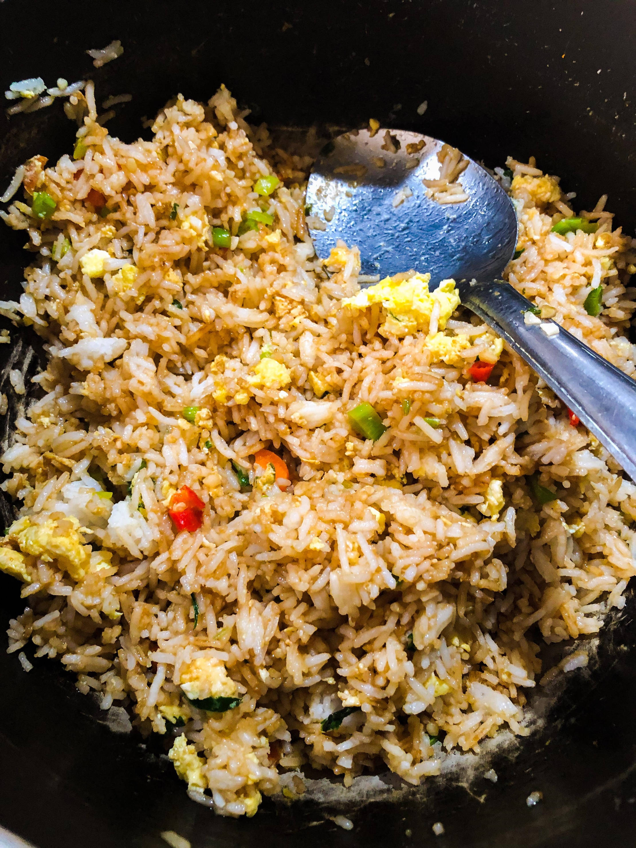 烹飪 桌布 壁紙 — 金色炒飯配炒蛋和色彩繽紛的蔬菜，放在黑色鑊中，附有金屬湯匙的特寫。