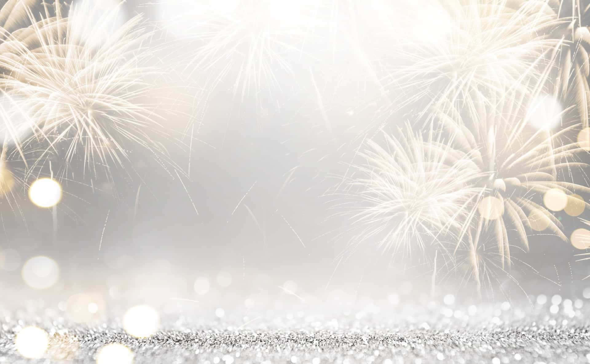 New Years Eve 桌布 壁紙 — 金色煙火在朦朧的天空中綻放，下方是閃爍的銀色表面，帶有柔和的散景燈光。